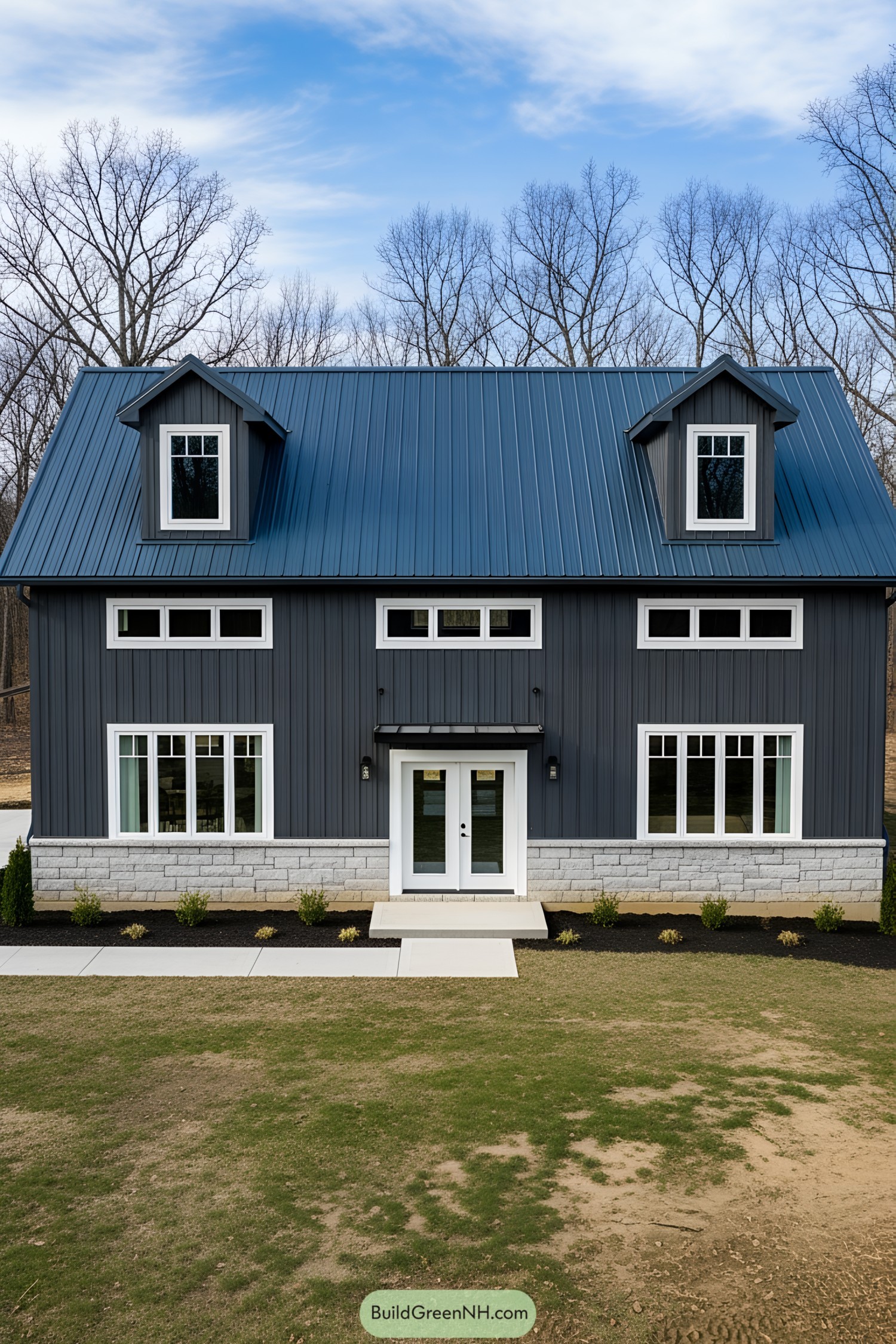 Dark gray barn house with blue roof and trees in the background