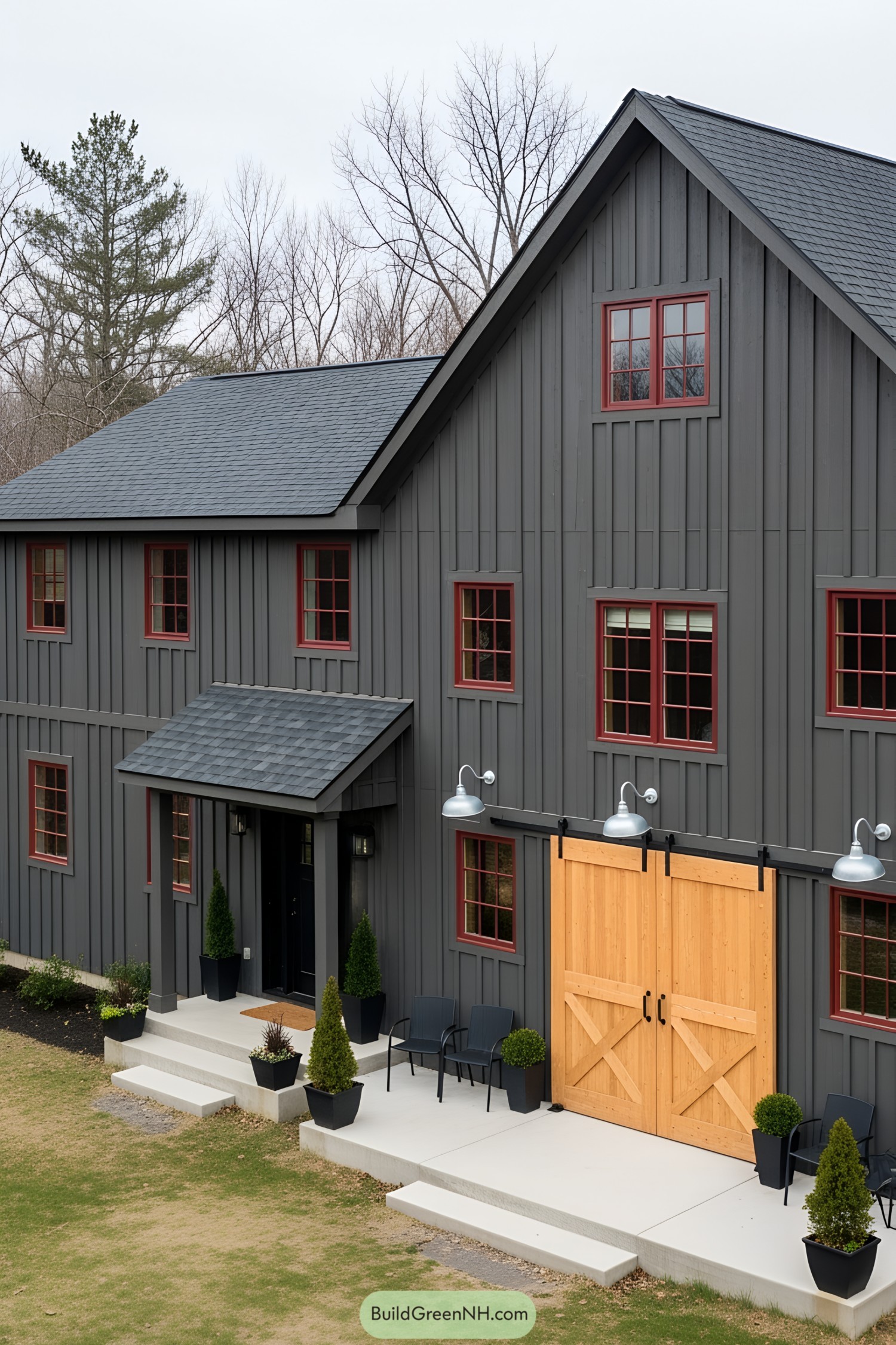A dark gray barn house with red-framed windows and wooden barn doors