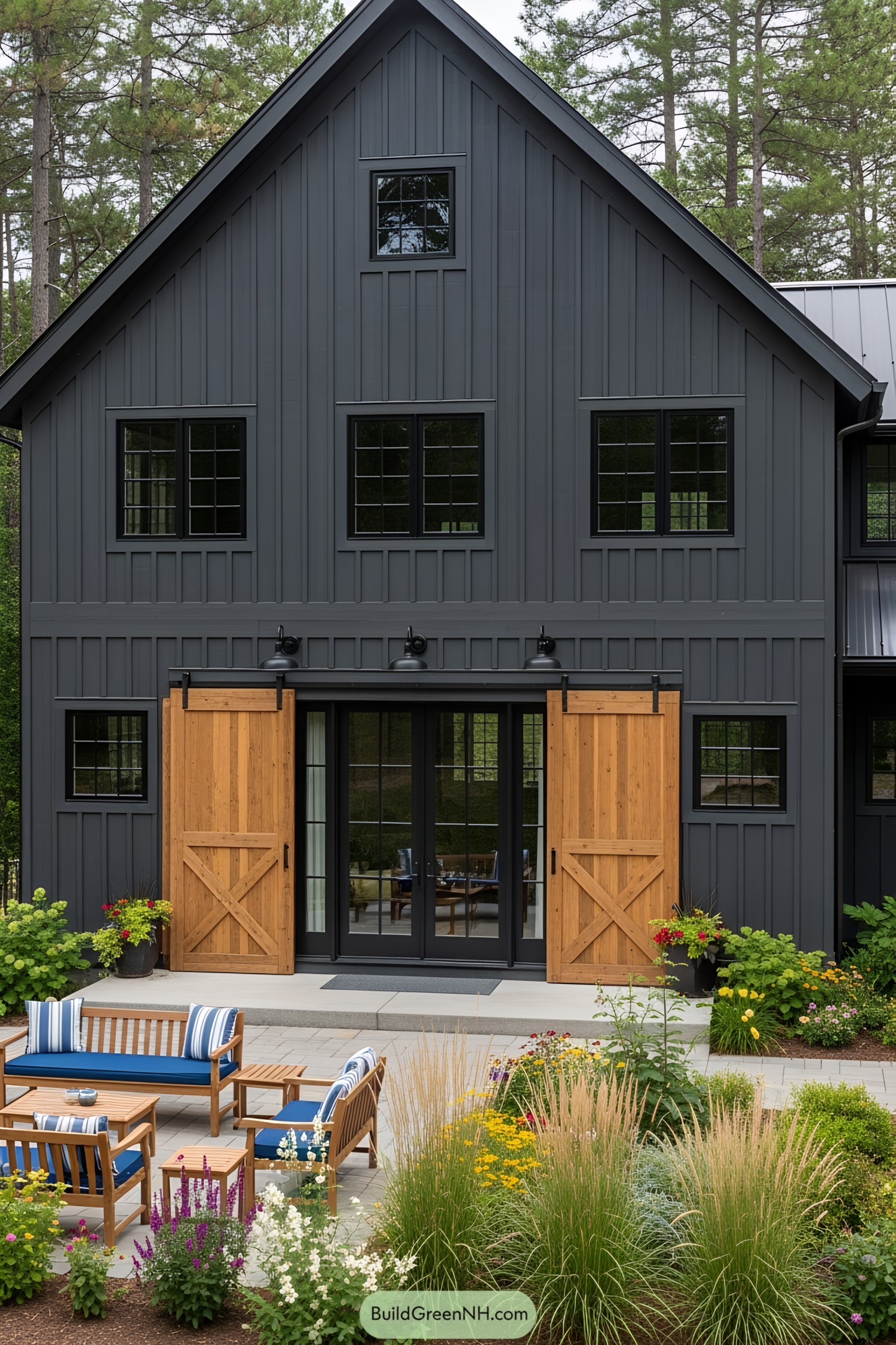 Dark gray barn house with wooden doors and lush patio