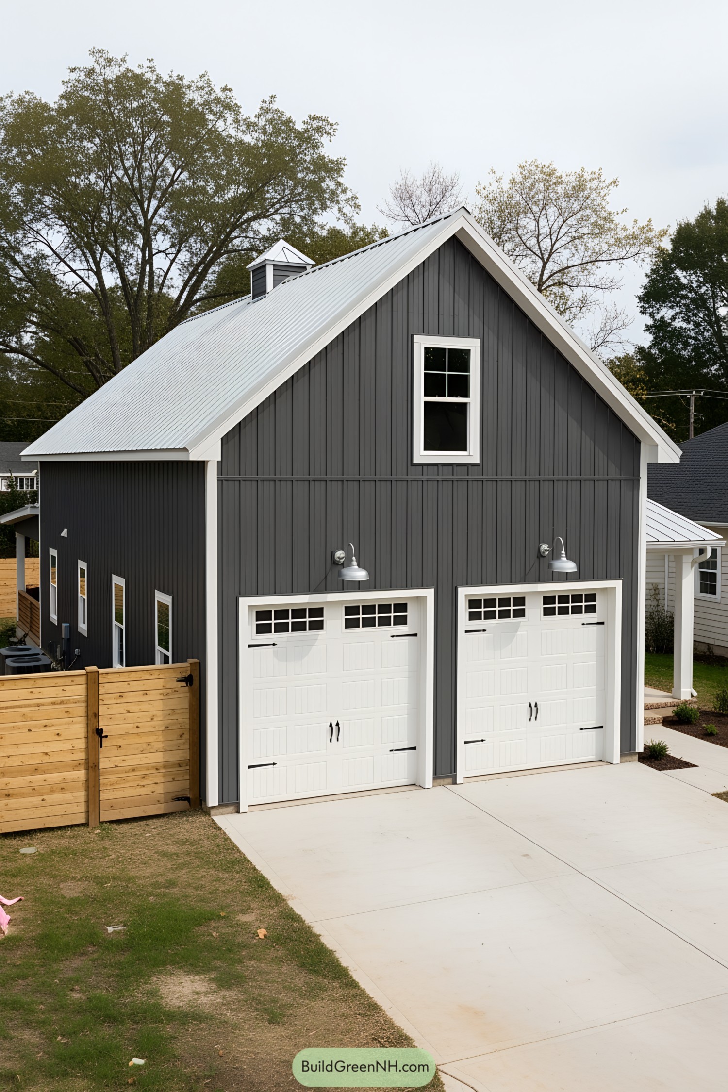 Dark gray barn house with white garage doors