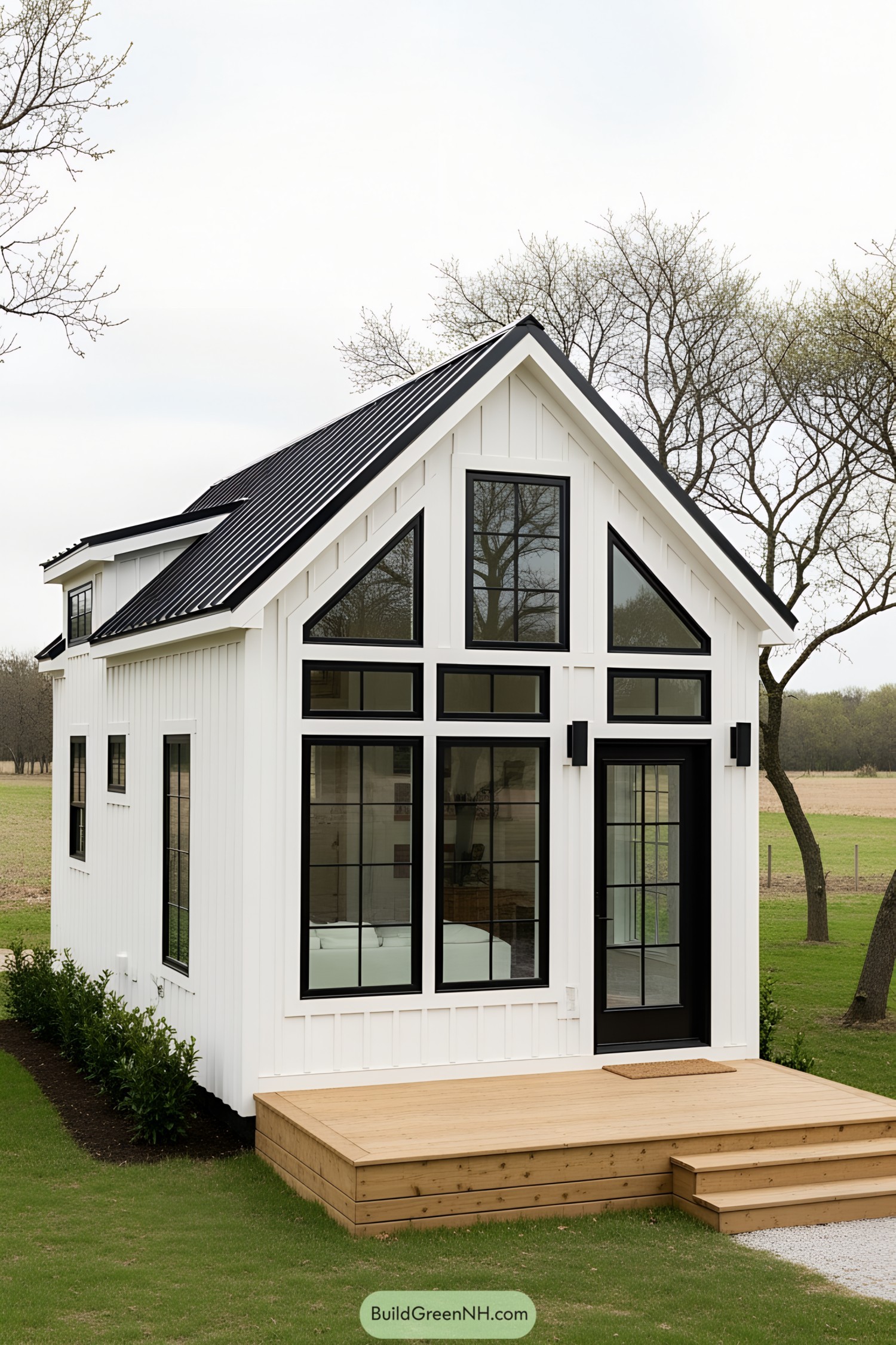 White farmhouse tiny house with large windows and wooden porch