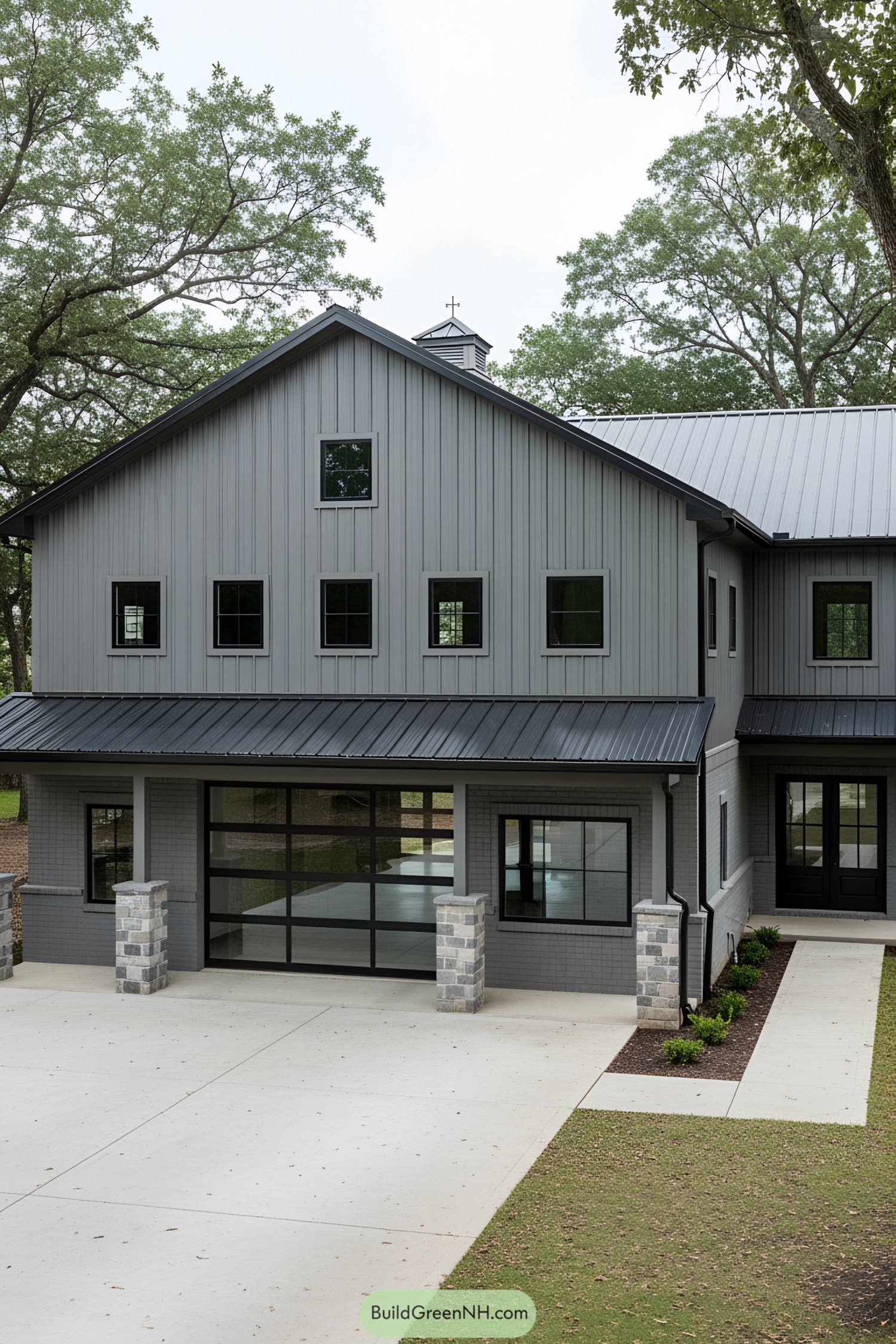 Modern gray barndominium under trees