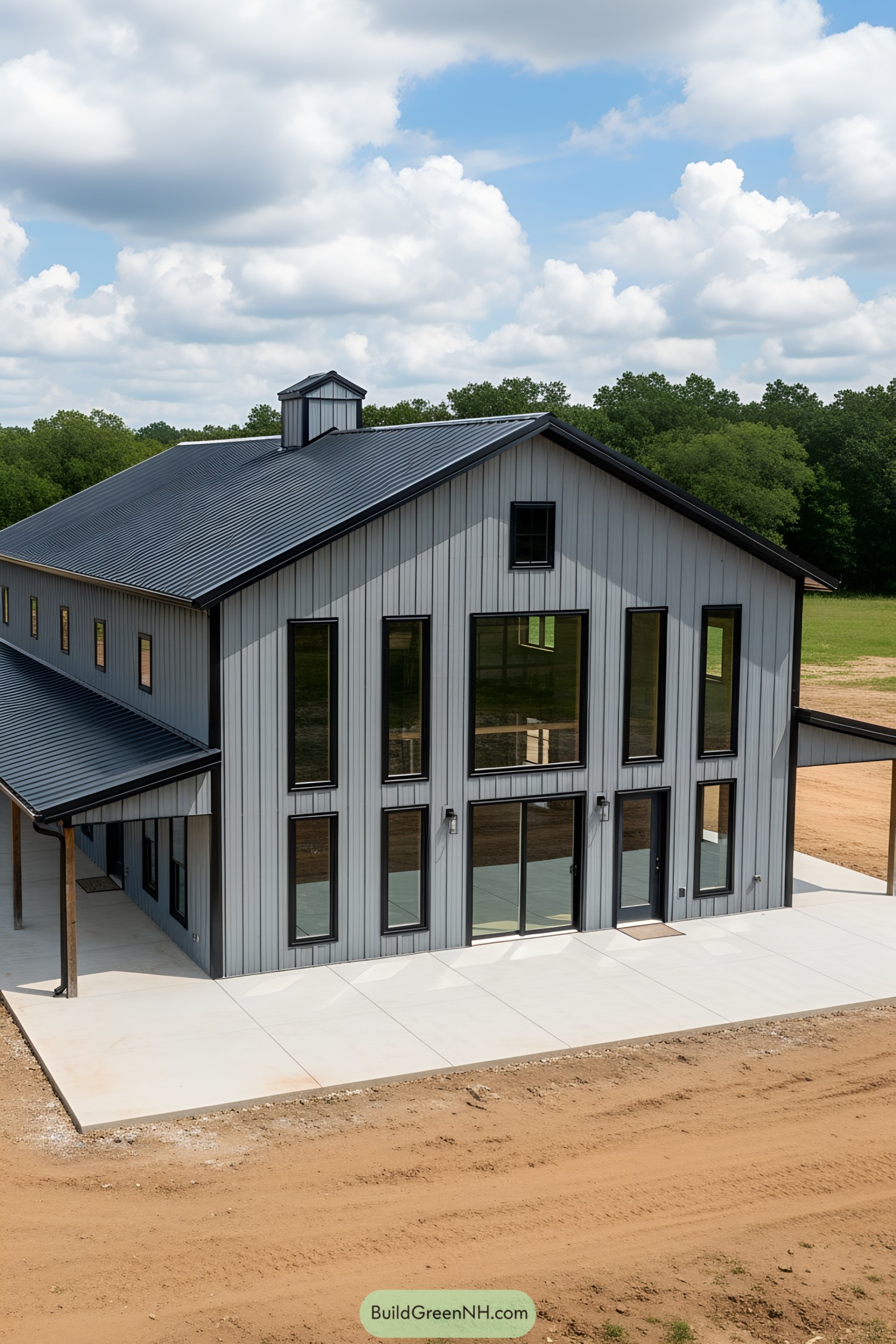 Gray barndominium with tall windows and lush surroundings