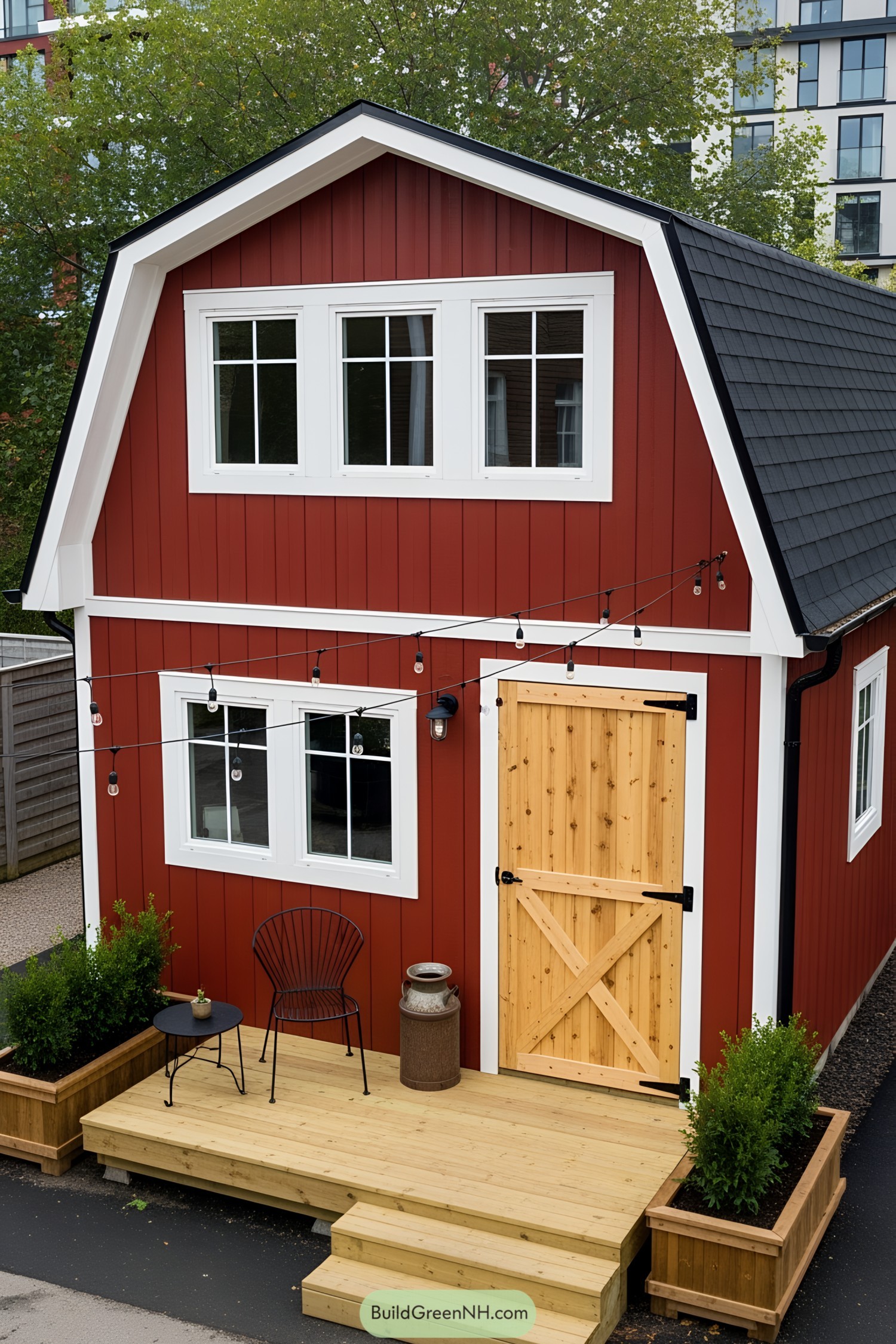Red barn-style tiny house with string lights and wooden deck