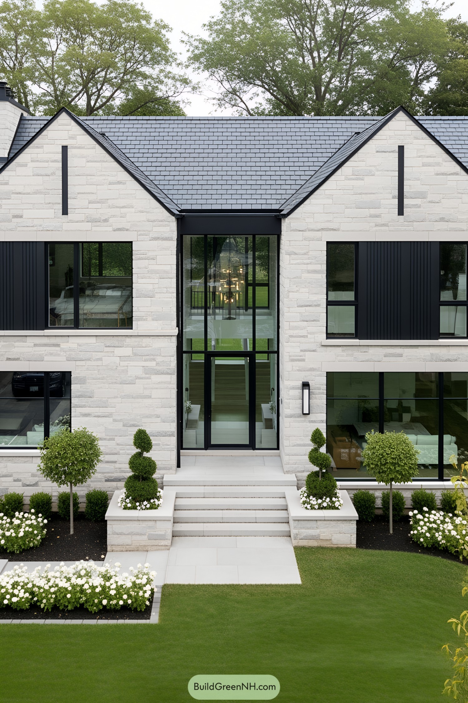 Modern stone house with large windows and manicured garden