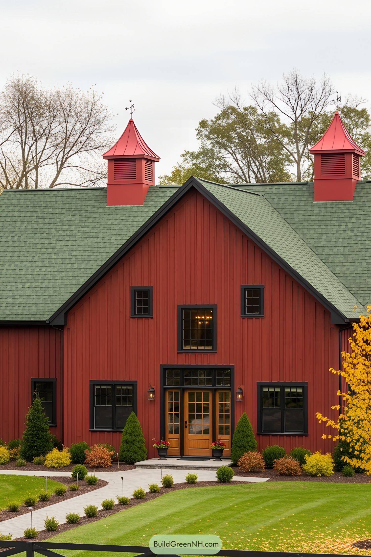 Red barn house with green roof and surrounding garden