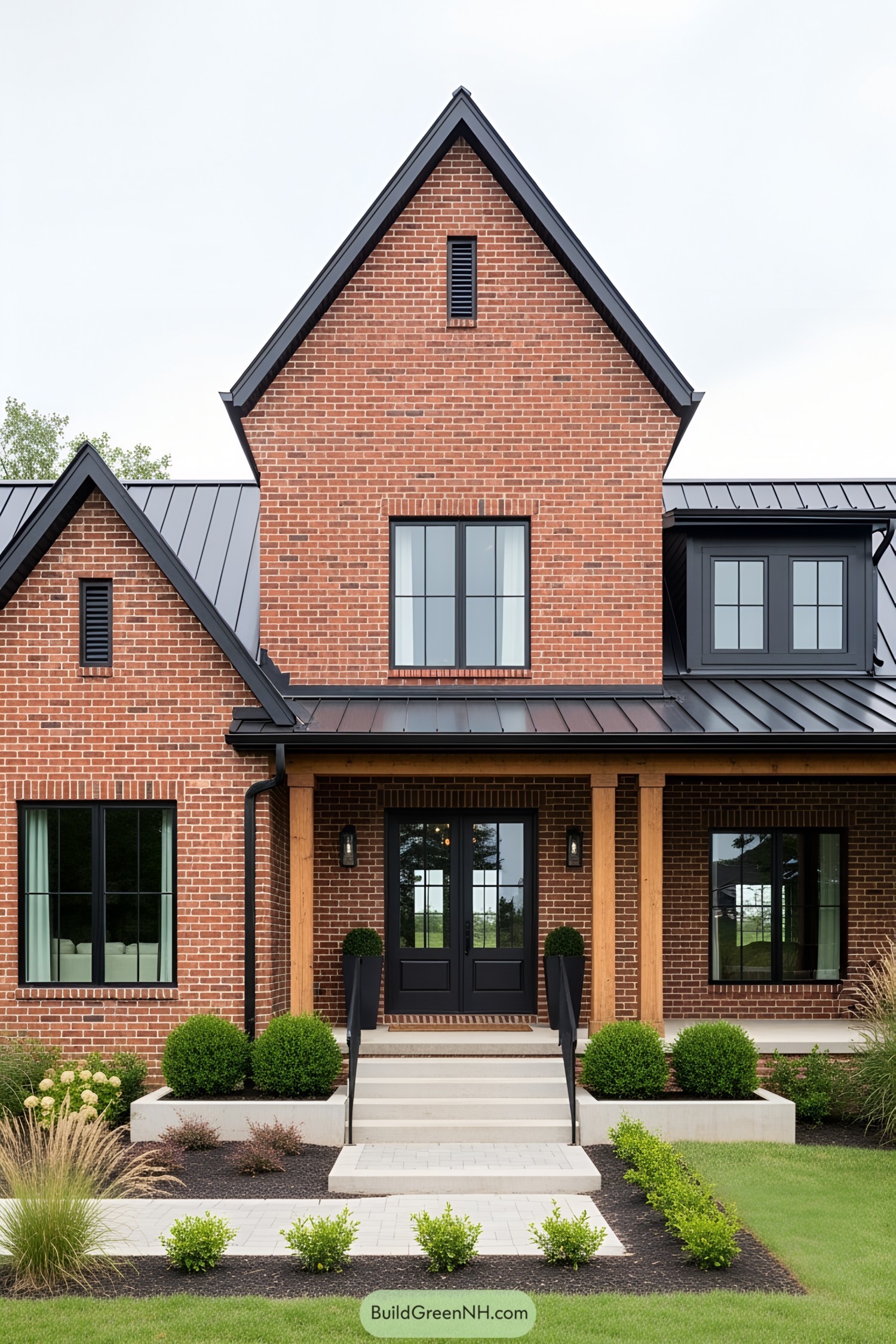 Elegant red brick farmhouse with black-framed windows and lush greenery