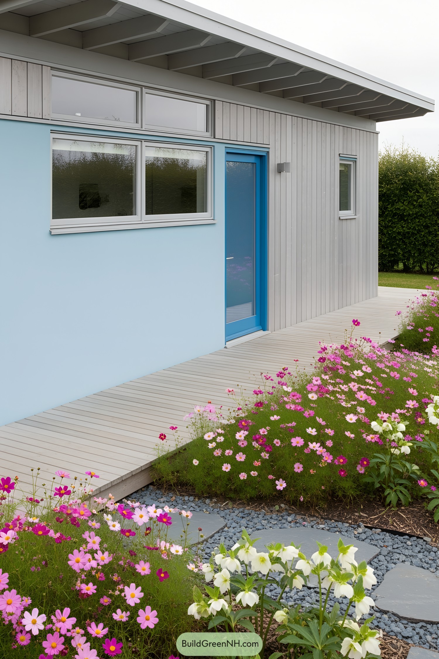 A modern tiny house with a deck surrounded by vibrant flowers