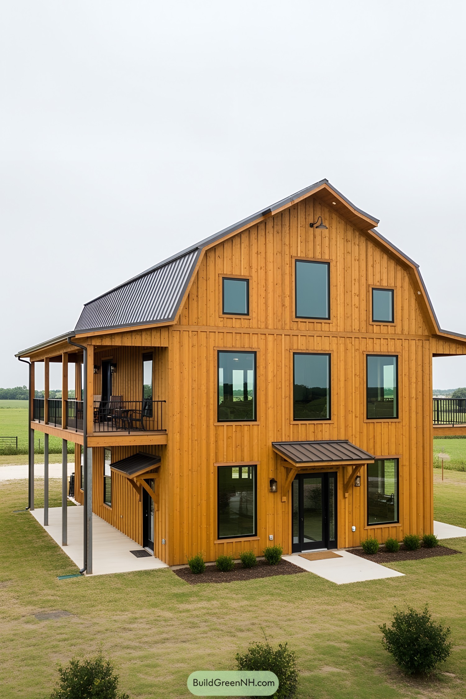 A tall barndominium with wooden siding and large windows set in a field
