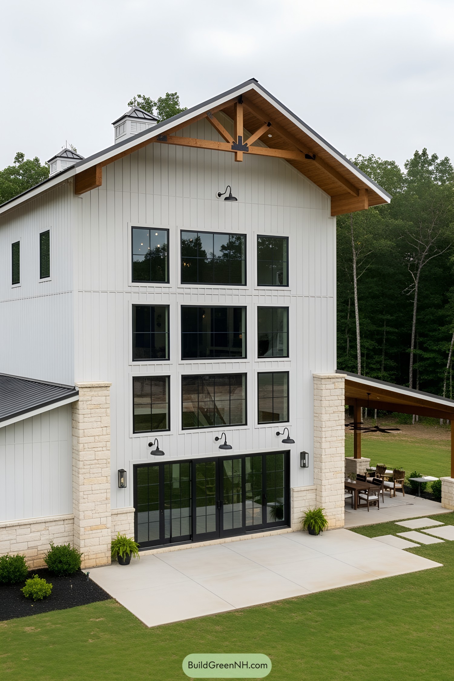 Tall white barndominium with large windows and a gabled roof