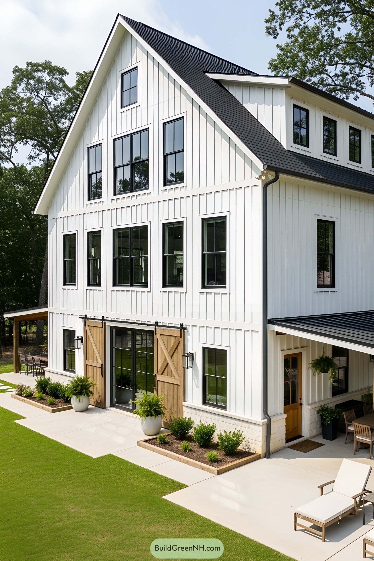 Tall white barndominium with black windows and rustic wooden doors
