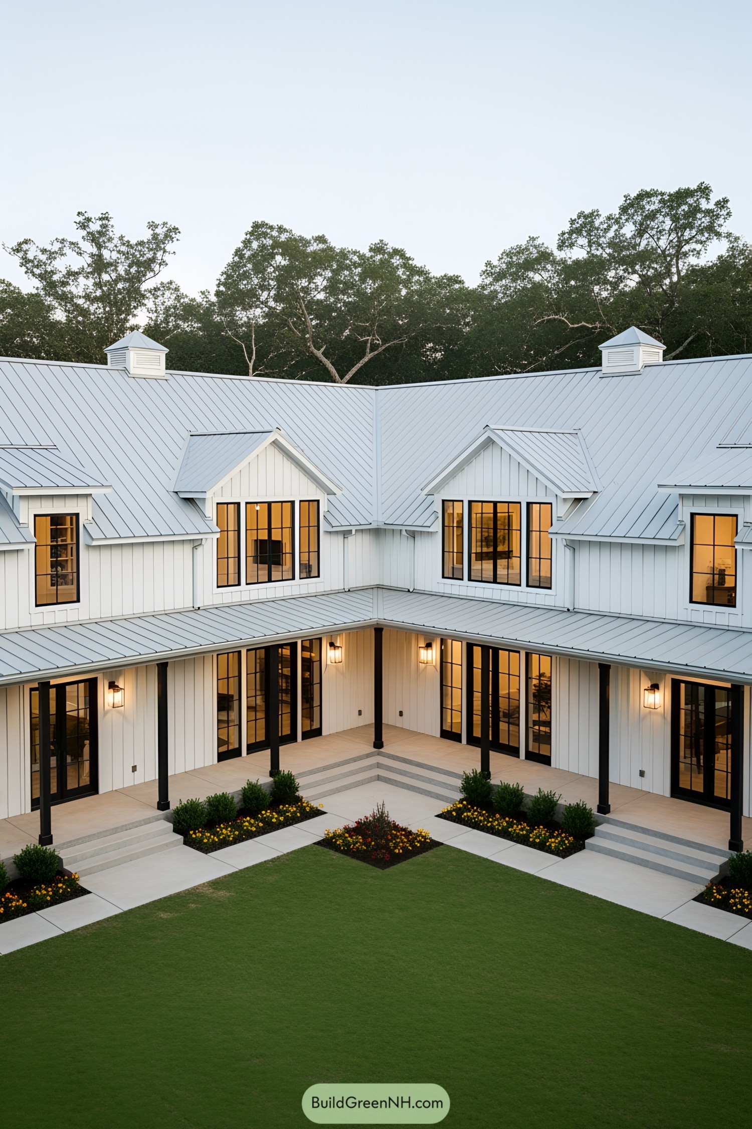 Charming white barndominium with a U-shaped design and lush greenery