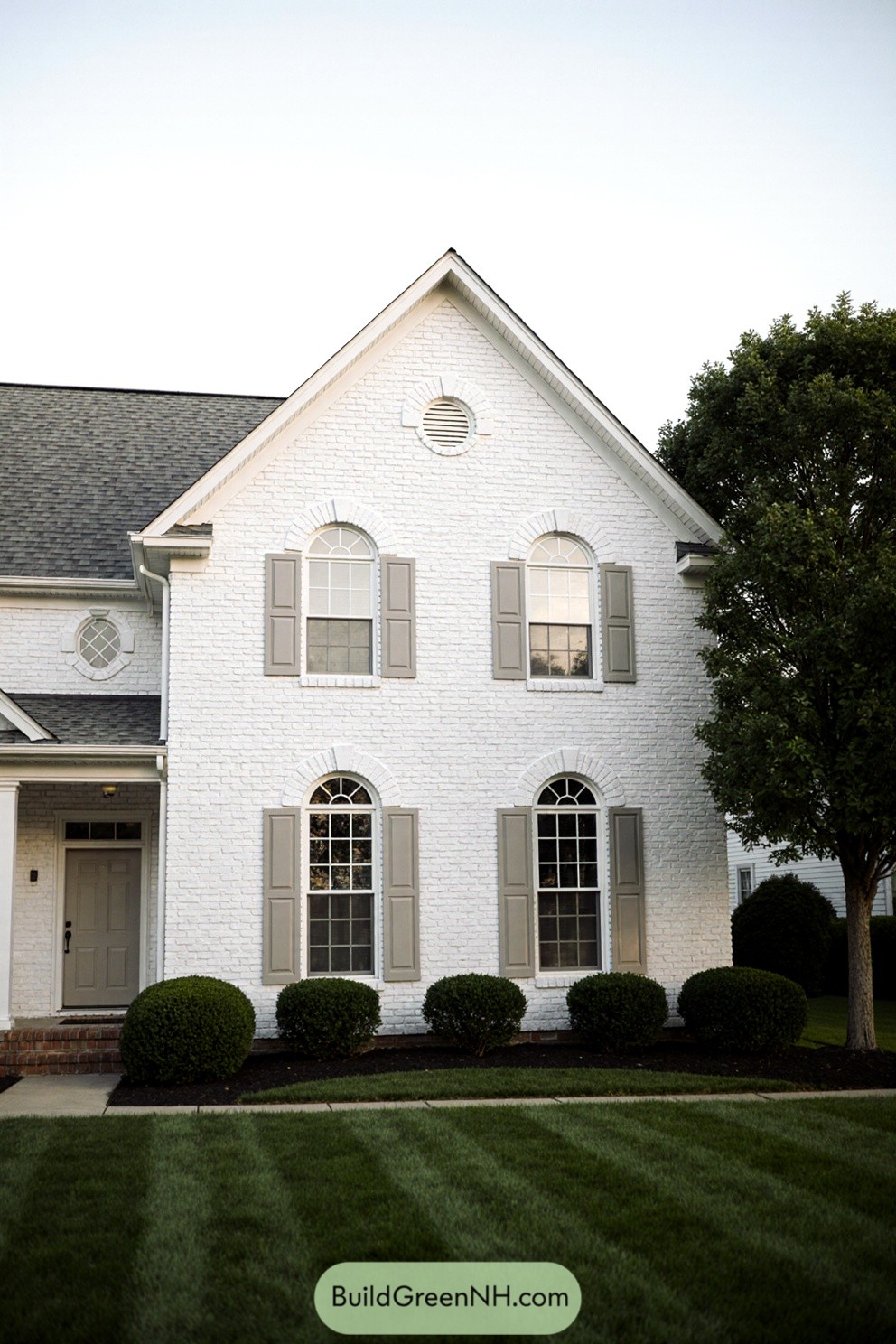 White brick house with classic arched windows and shutters
