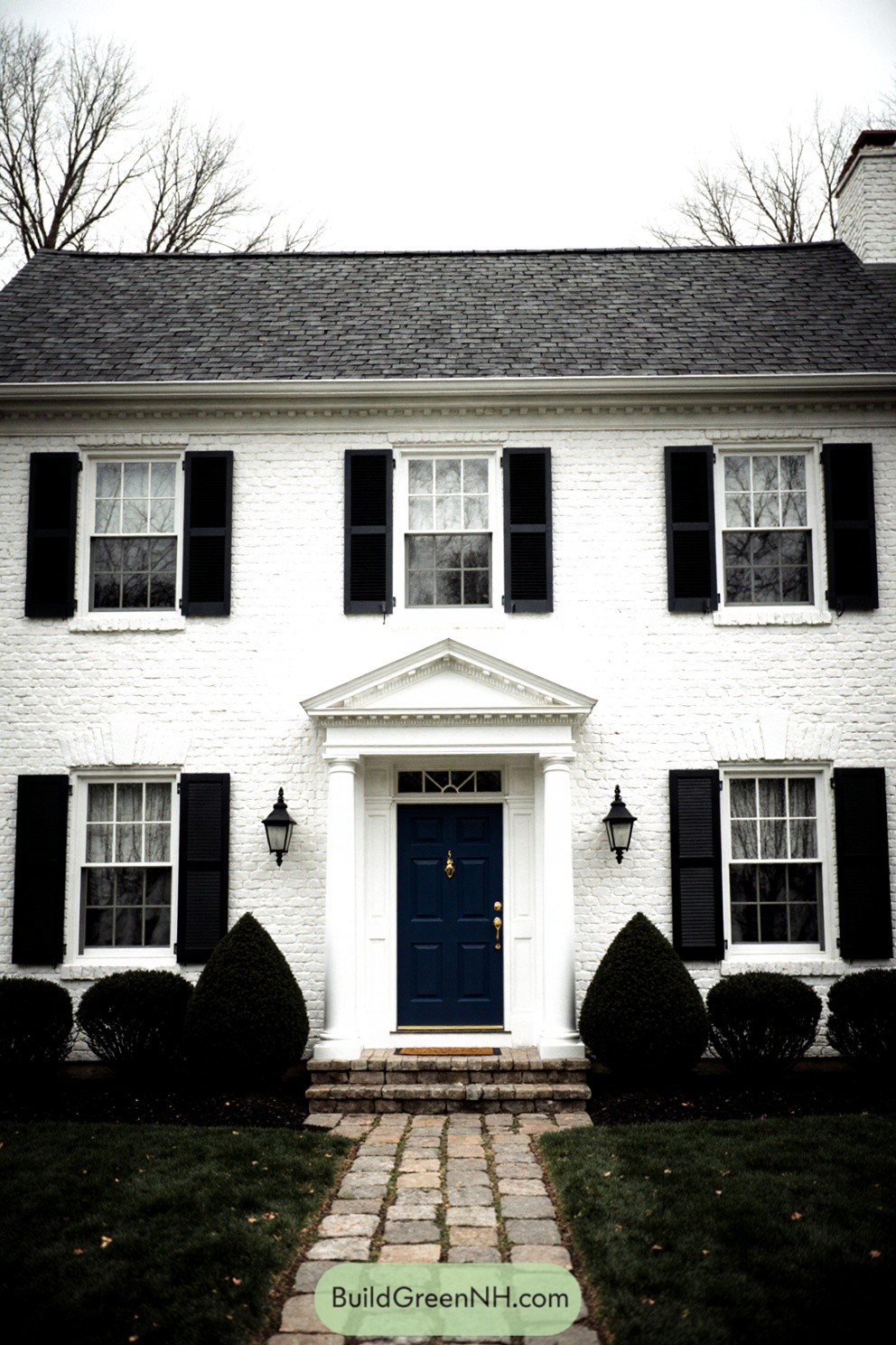 White brick house with navy door and dark shutters