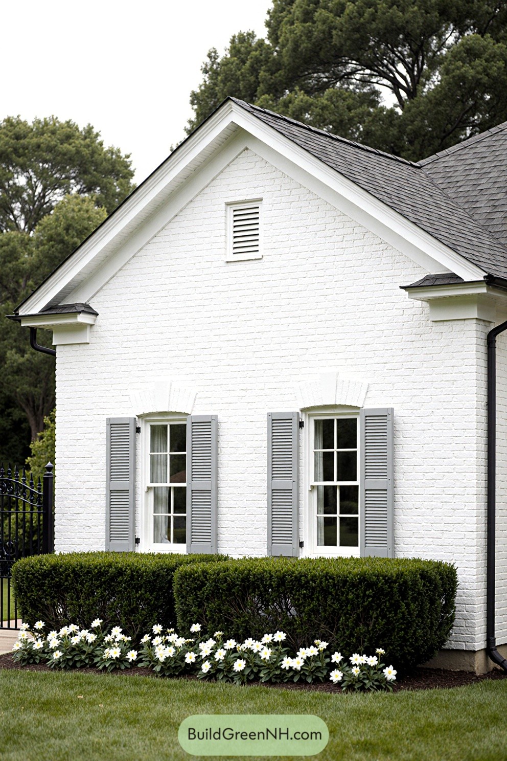 White brick house with gray shutters and lush greenery