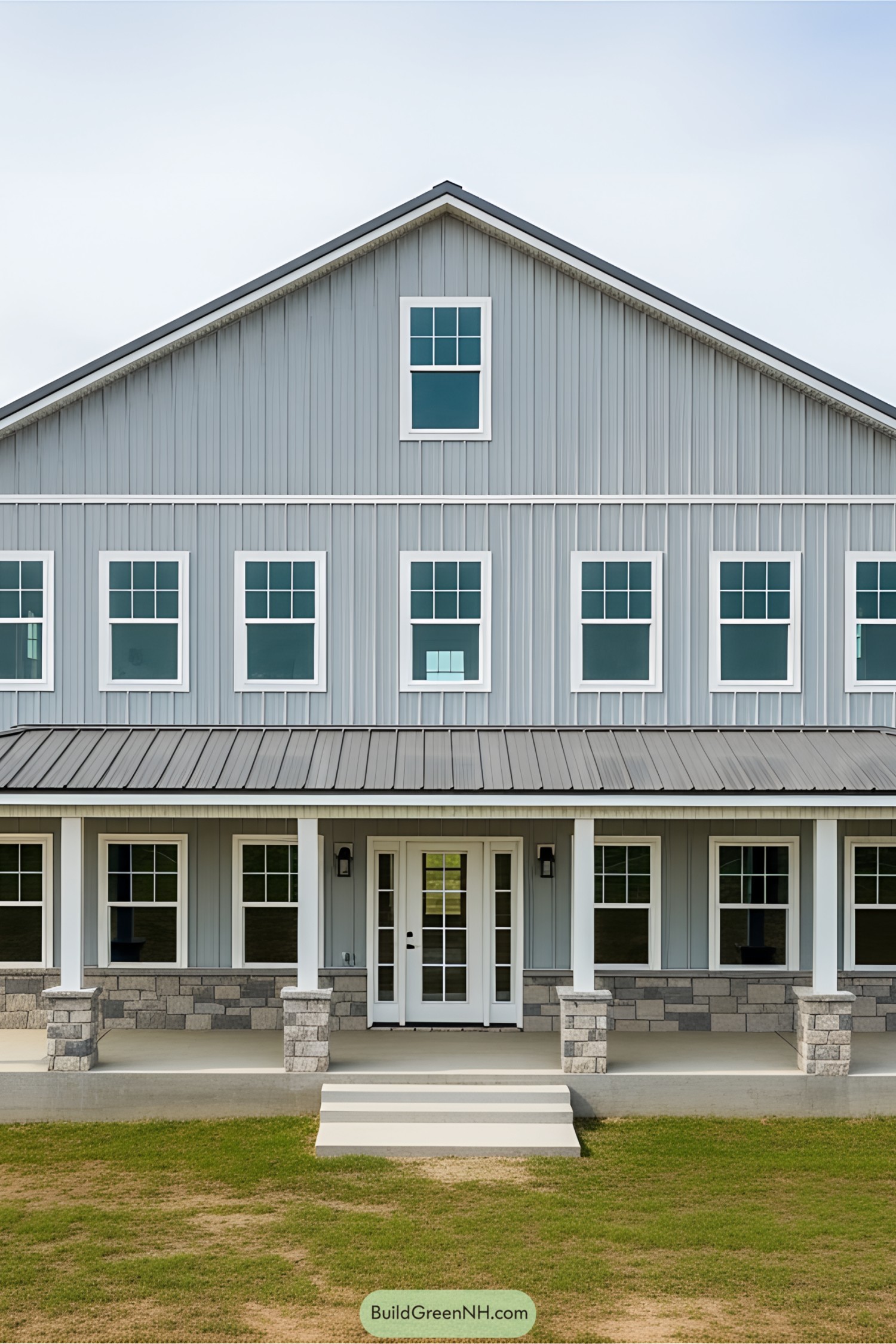 Large gray barndominium with symmetrical windows and stone foundation