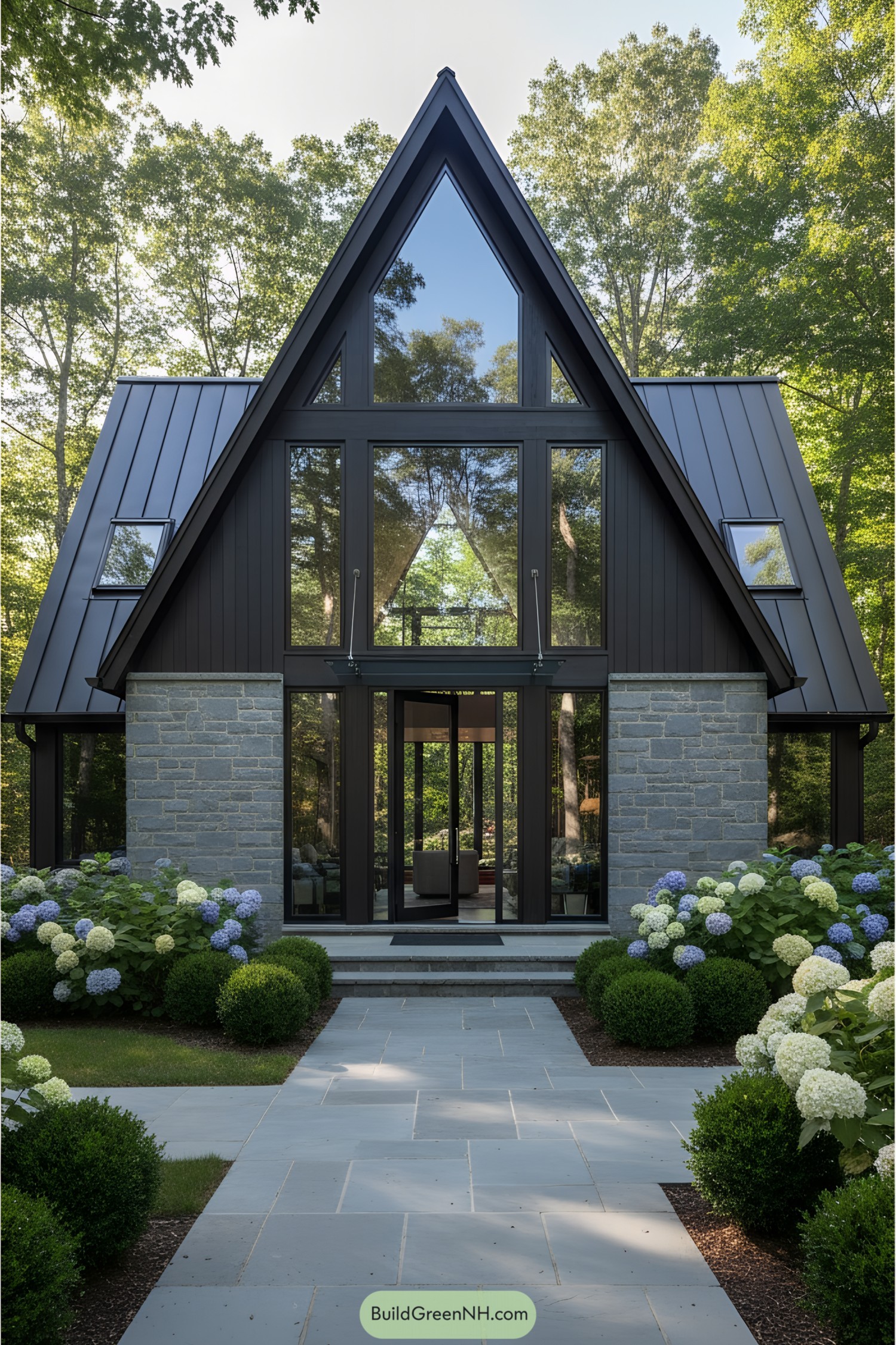 A modern A-frame house with stone facade and large glass windows surrounded by greenery
