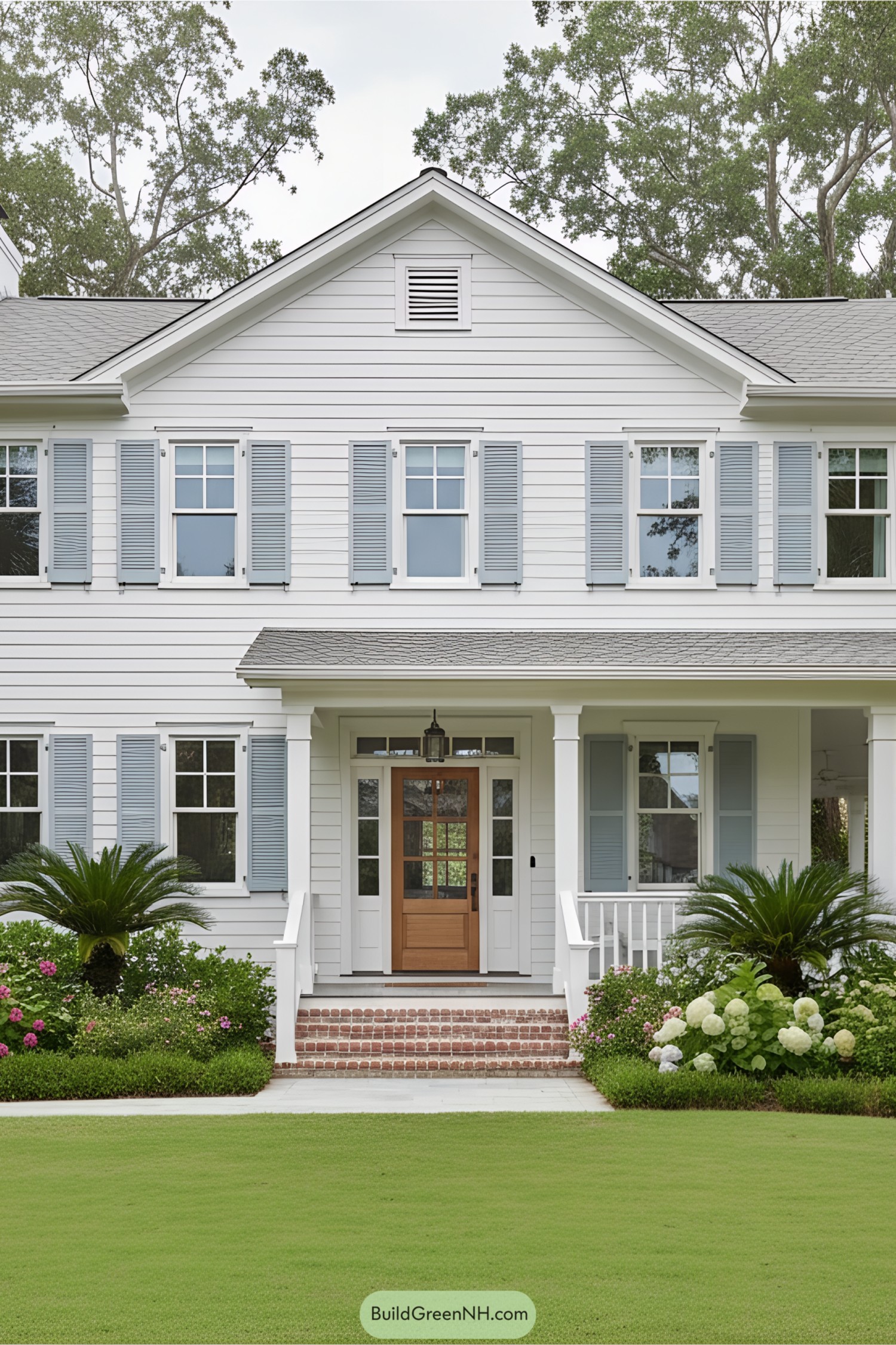 White beach house with light blue shutters and landscaped yard