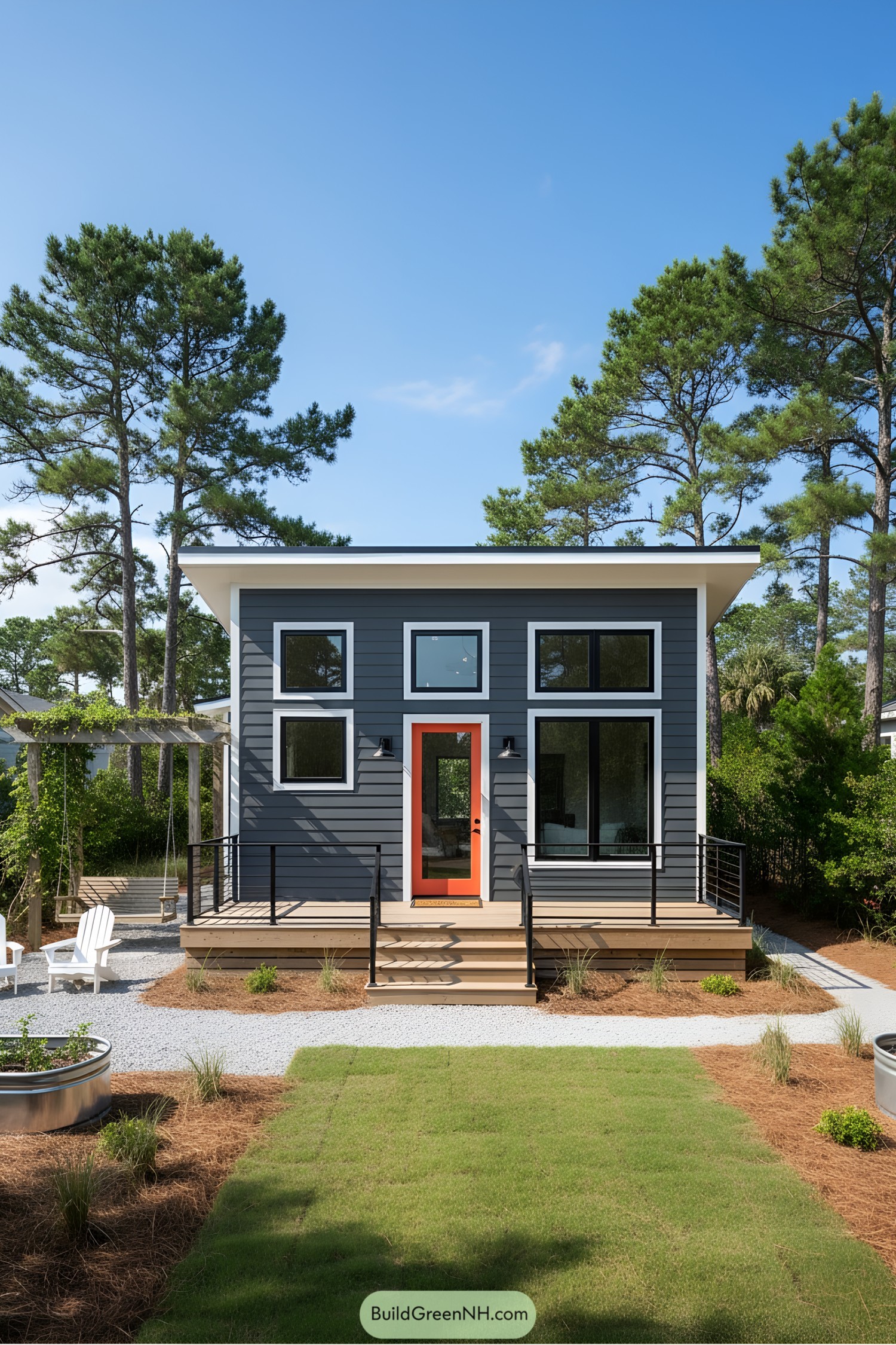 Modern beach cottage with a vibrant orange door and large windows surrounded by pine trees