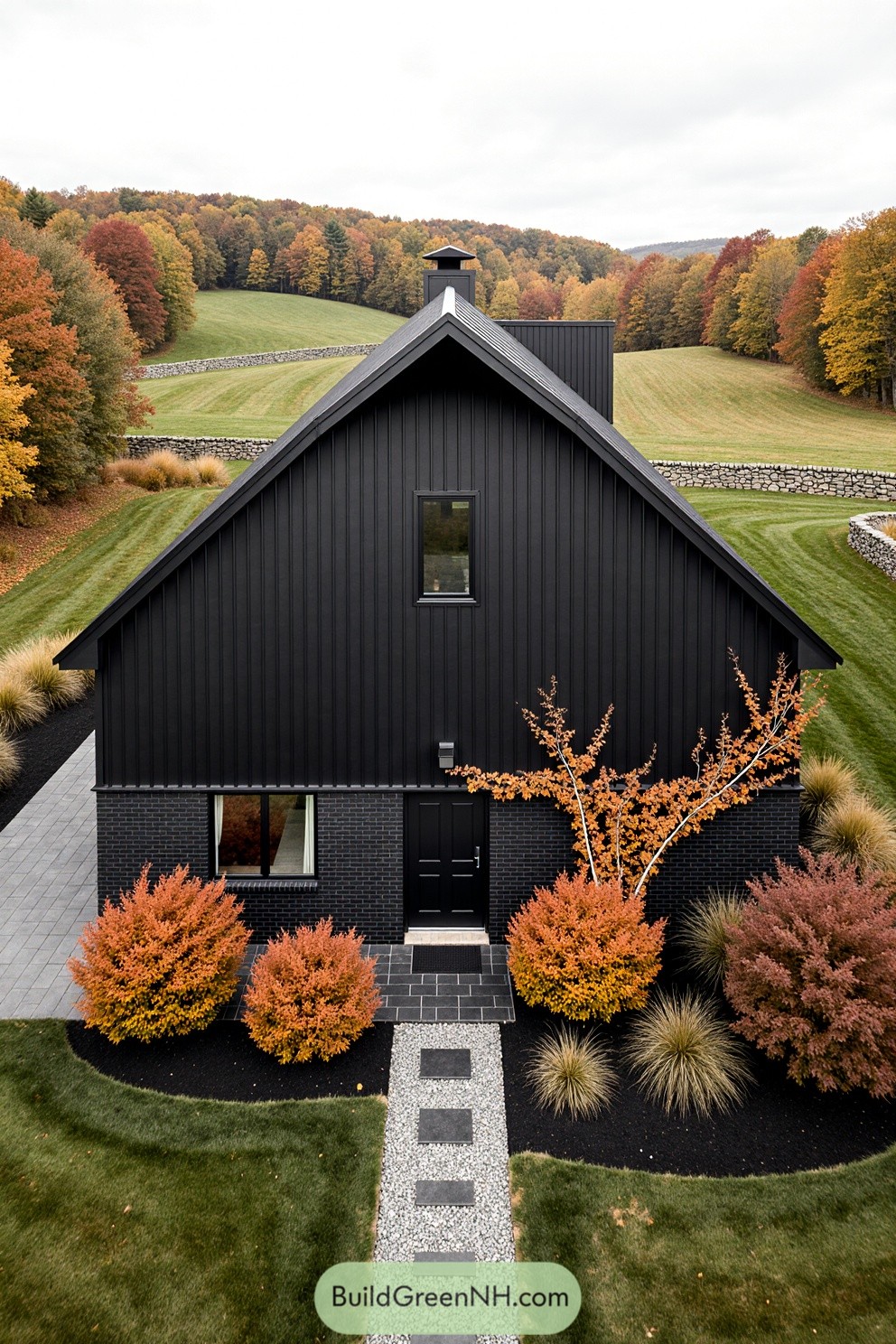 Aerial view of a black barndominium surrounded by vibrant fall colors
