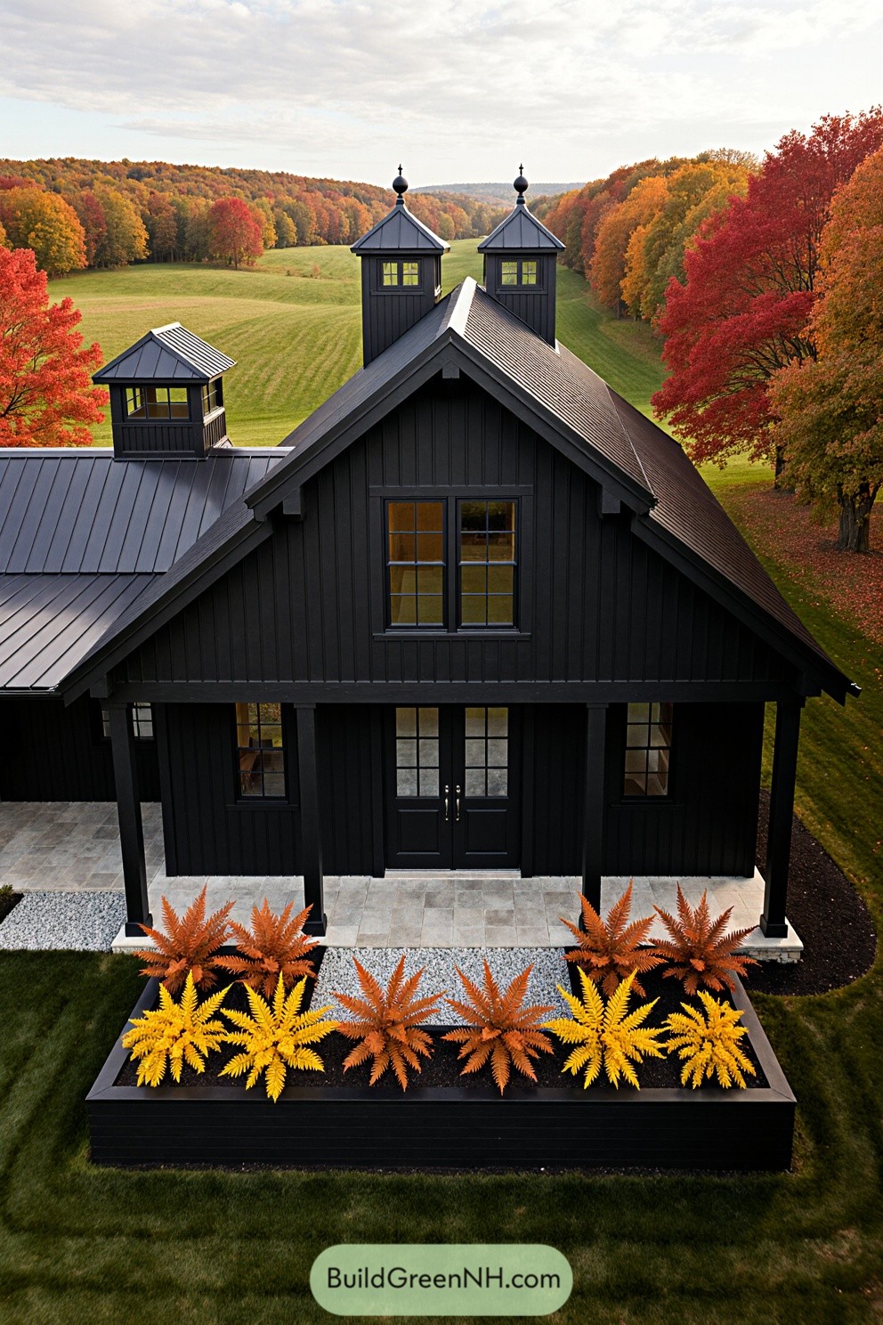 Aerial view of a black barndominium surrounded by colorful fall foliage