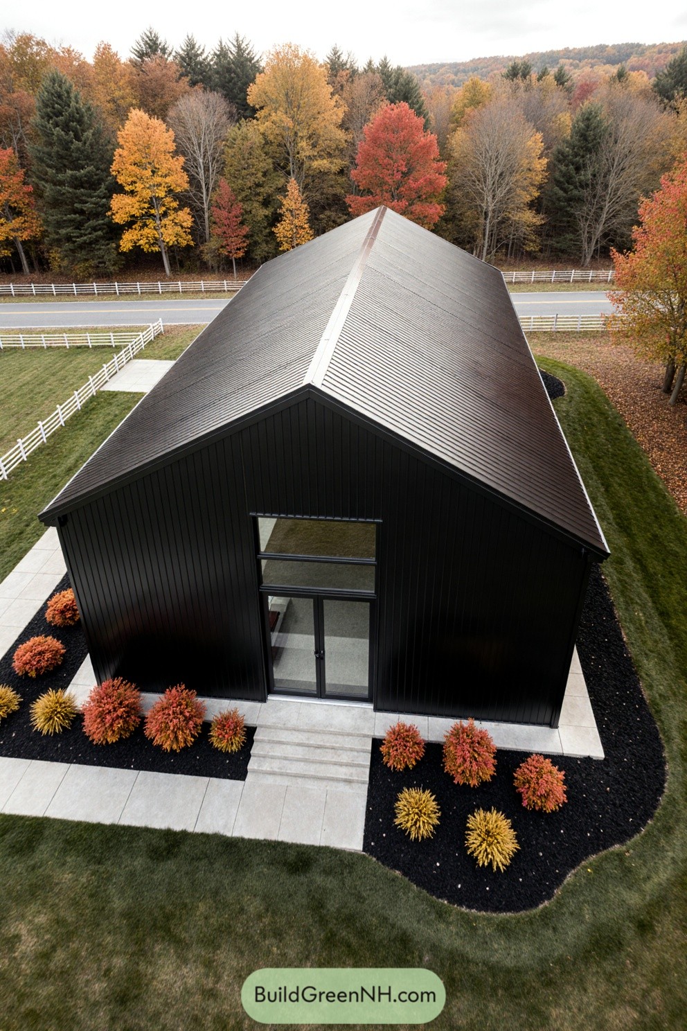 Aerial view of a sleek black barndominium surrounded by colorful autumn trees