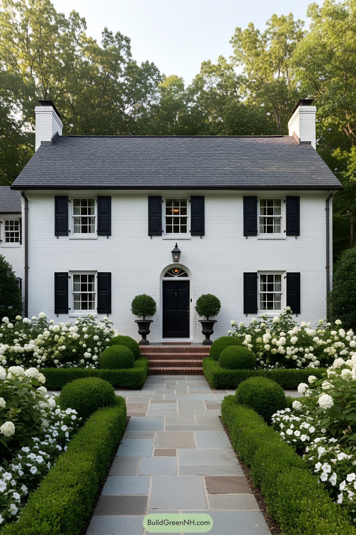 White brick cottage with black shutters and lush garden