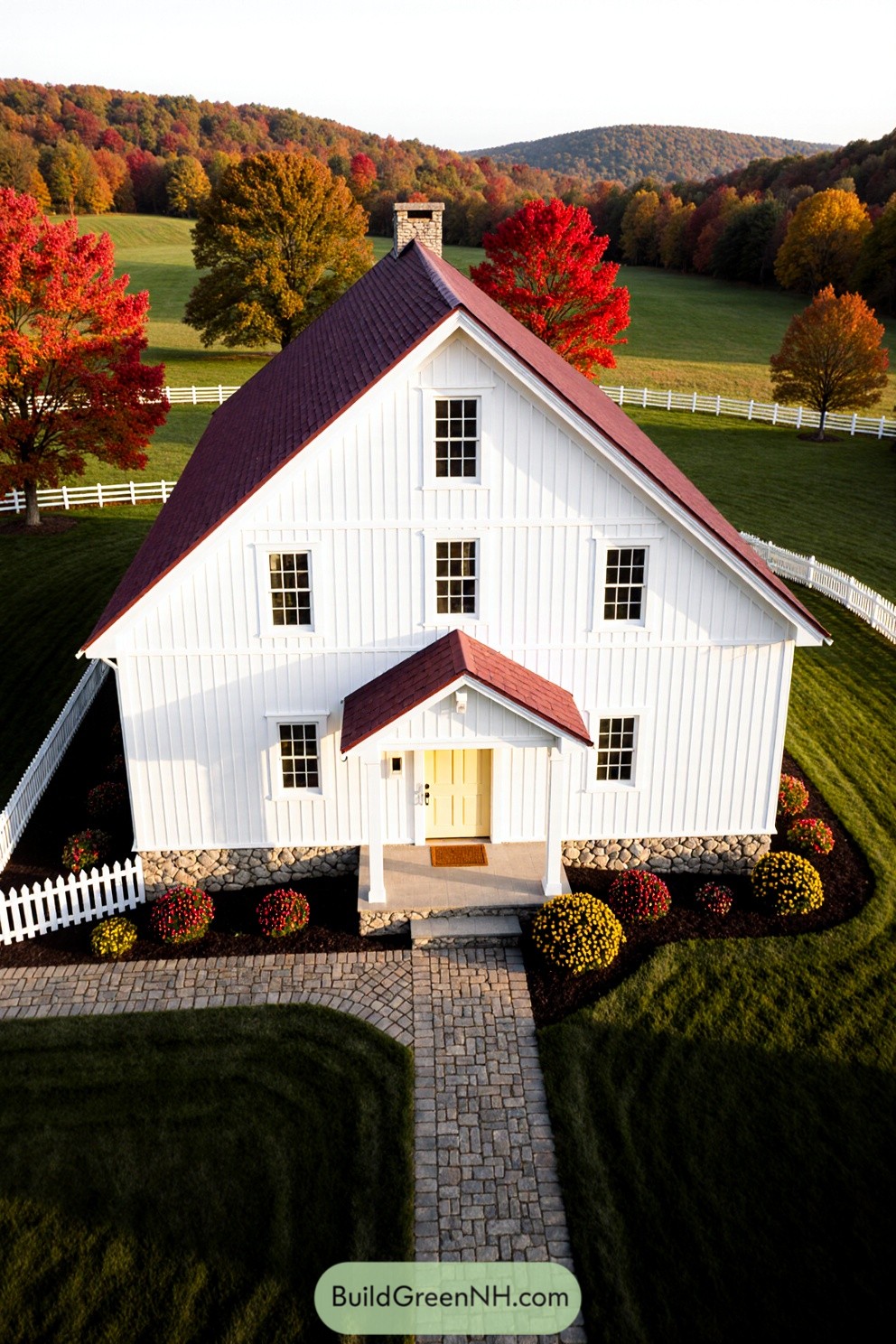 Aerial view of a charming white farmhouse framed by vibrant autumn trees