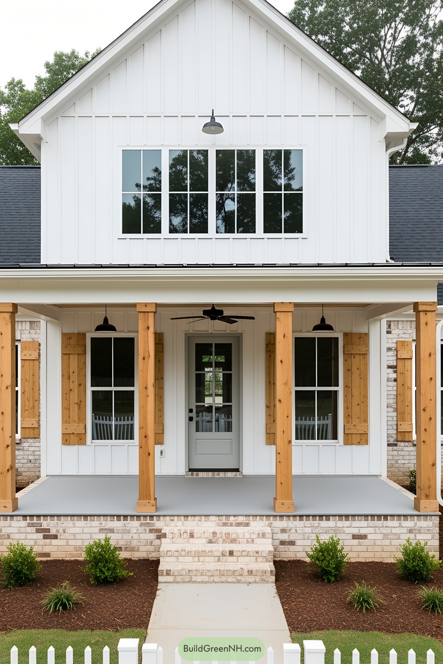 White farmhouse with wooden front porch and green shrubs