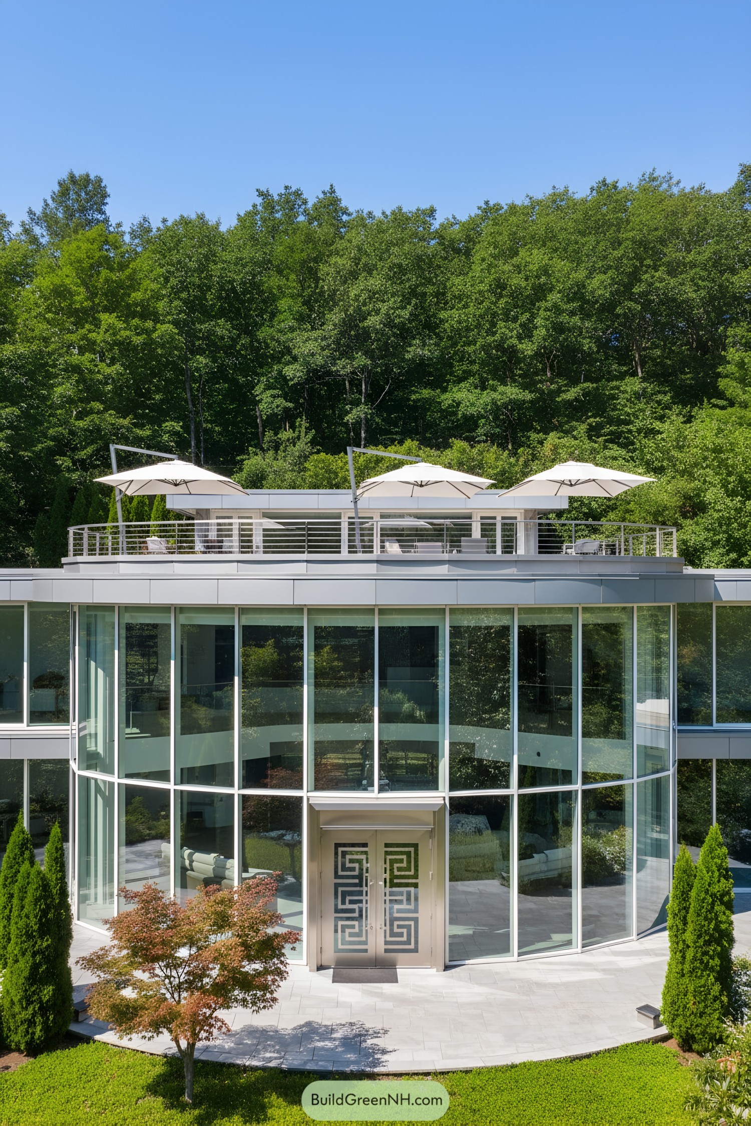 Modern glass house with rooftop terrace and umbrellas surrounded by greenery