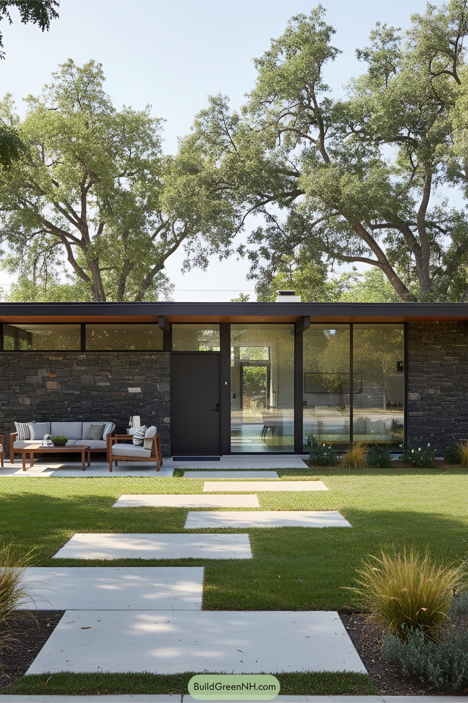 Modern ranch house with glass and stone exterior, surrounded by large trees