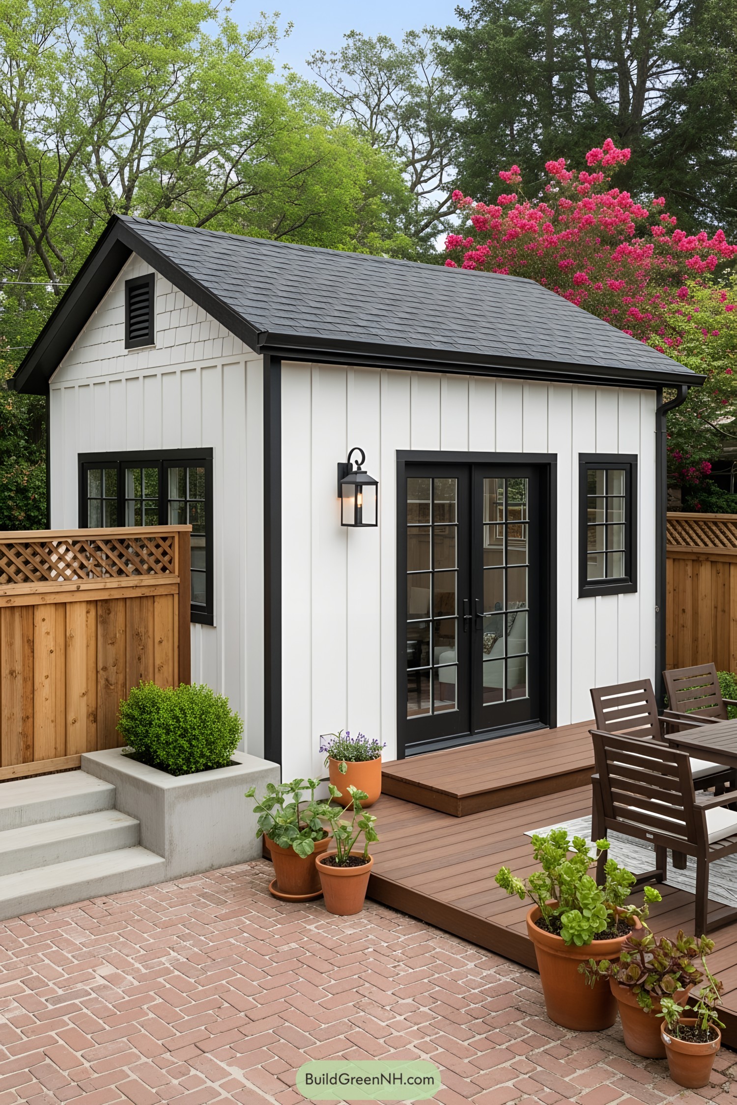 Small white cottage with black trim and potted plants