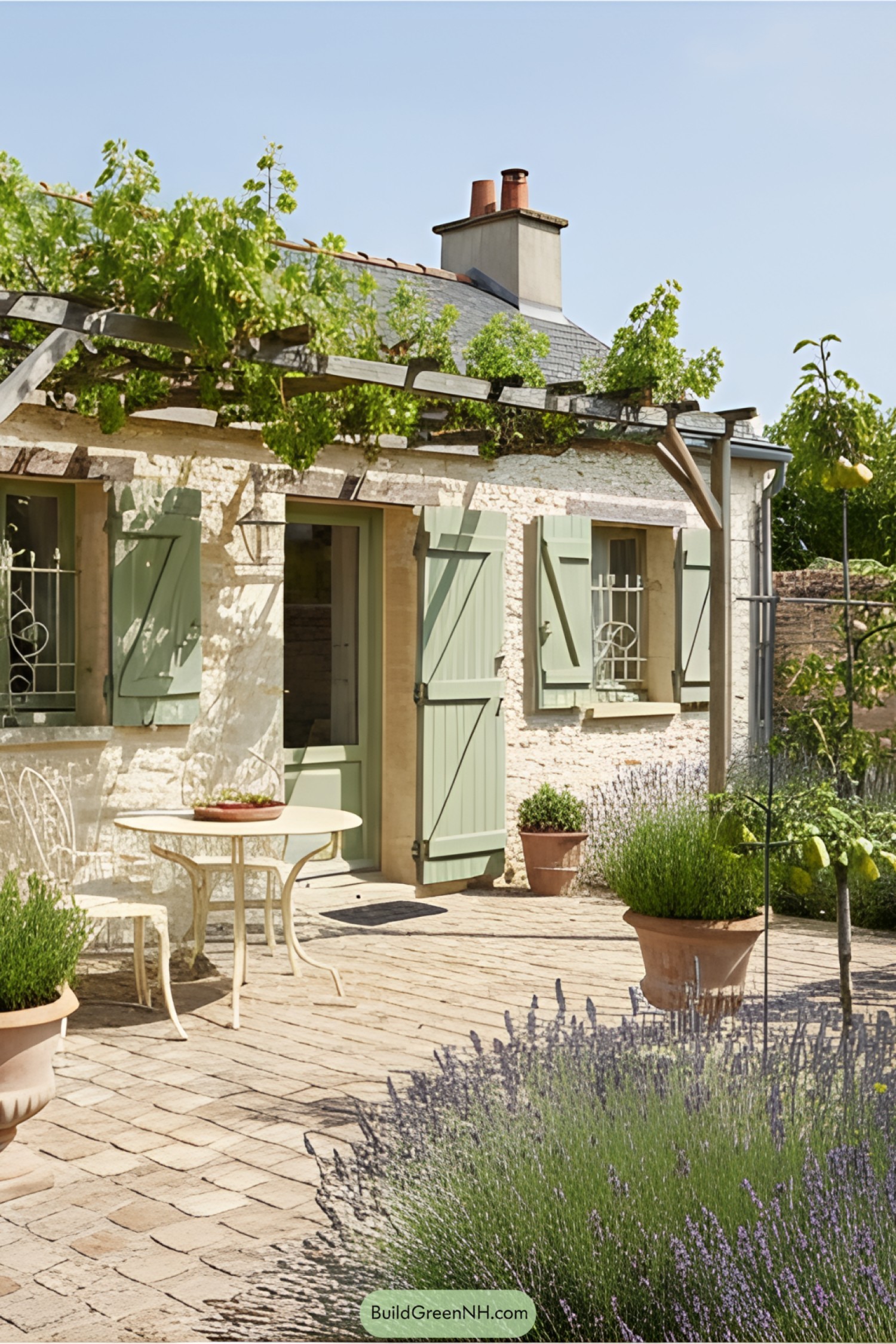 Tiny stone cottage with green shutters and garden patio