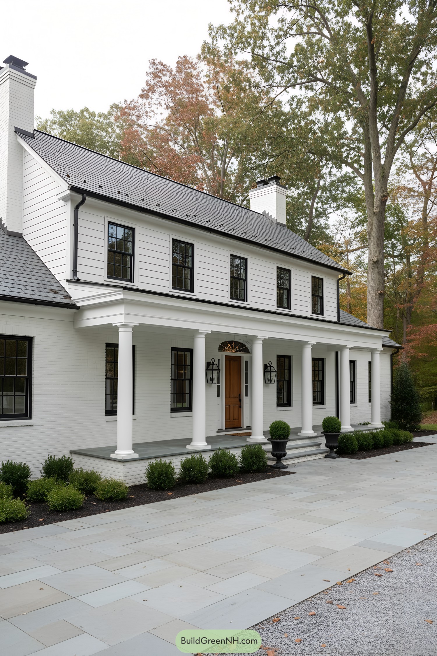 White brick colonial with slate roof, black windows, and a columned porch