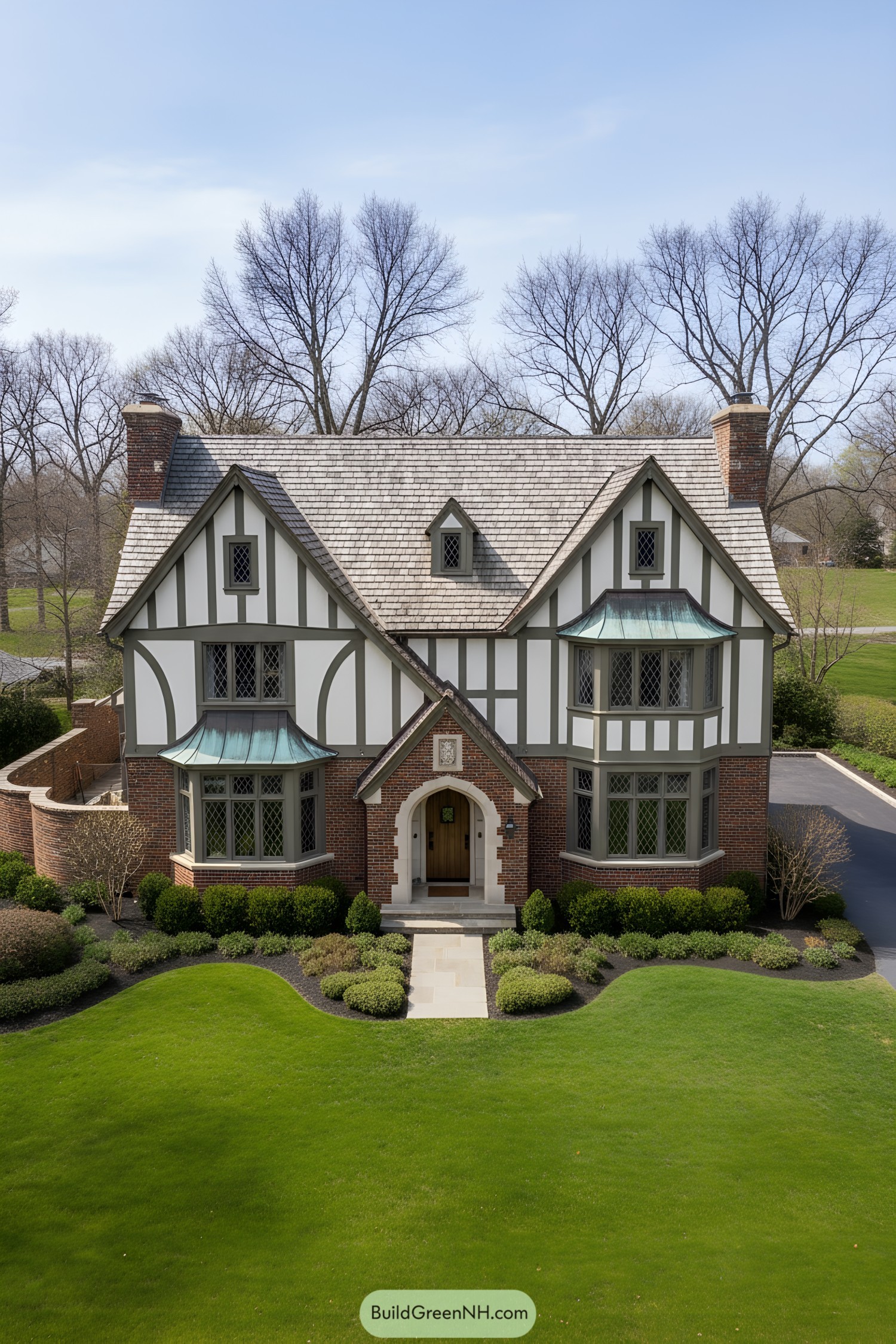 Tudor house with copper bay roofs, half-timbering, and brick base