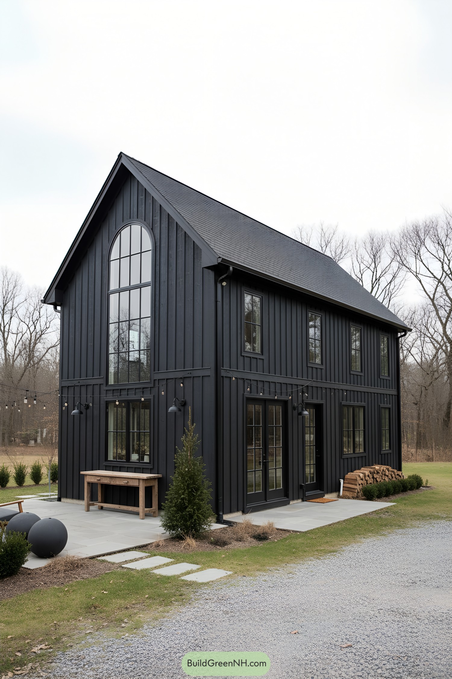 Black vertical-board barn with tall arched window and glass doors
