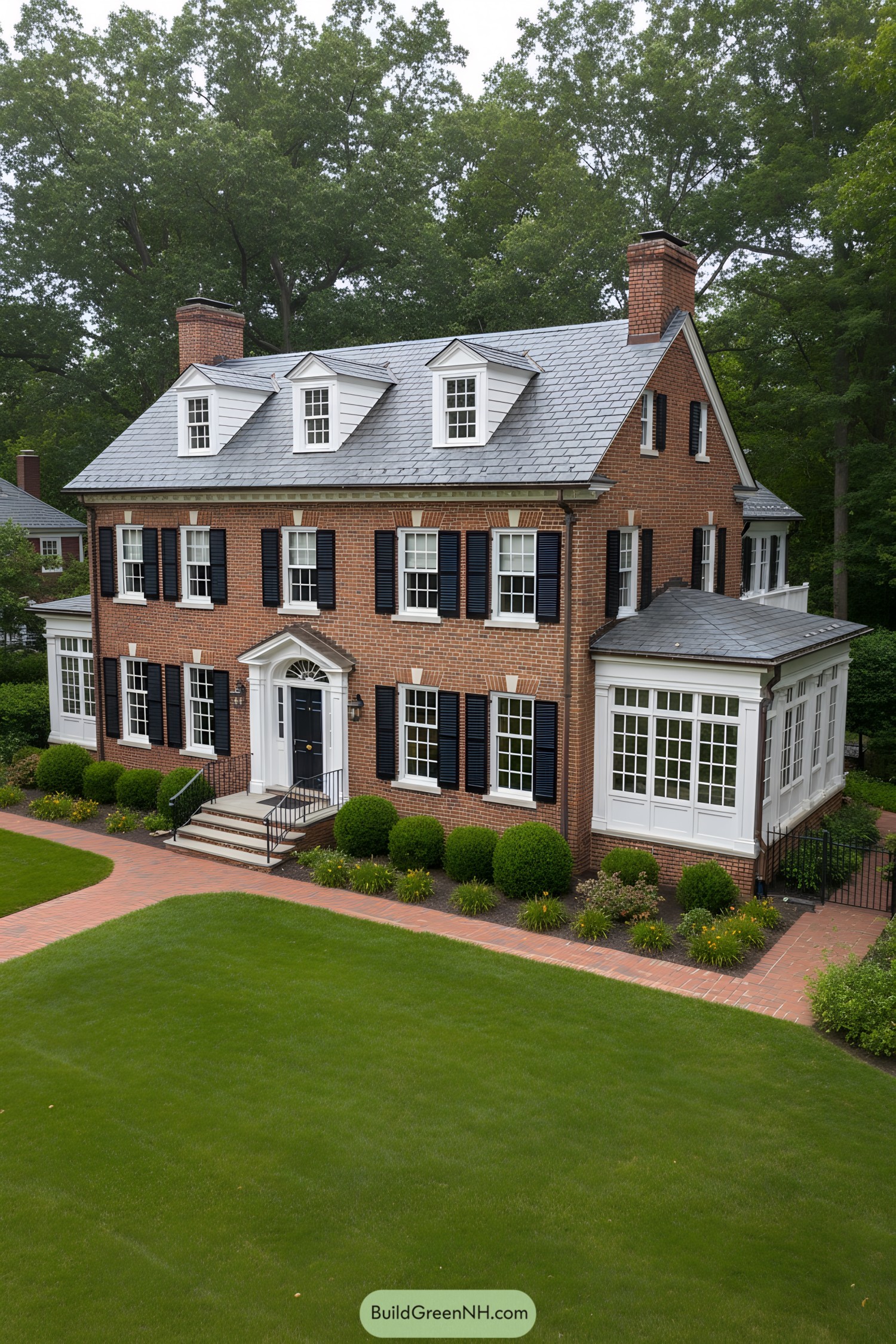 Red-brick colonial with slate roof, dormers, black shutters, and sunroom