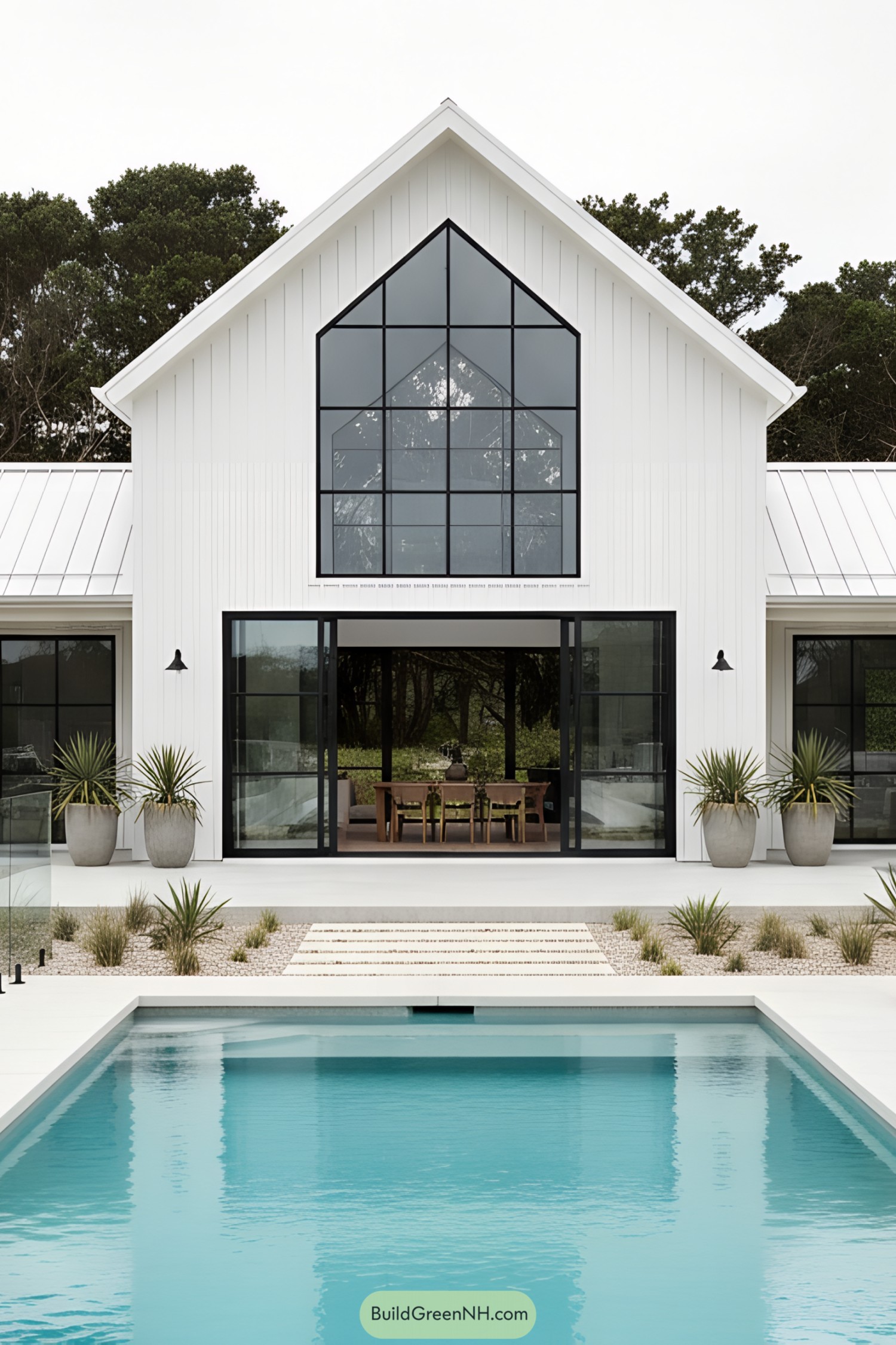 White coastal barn with black-framed gable window and pool