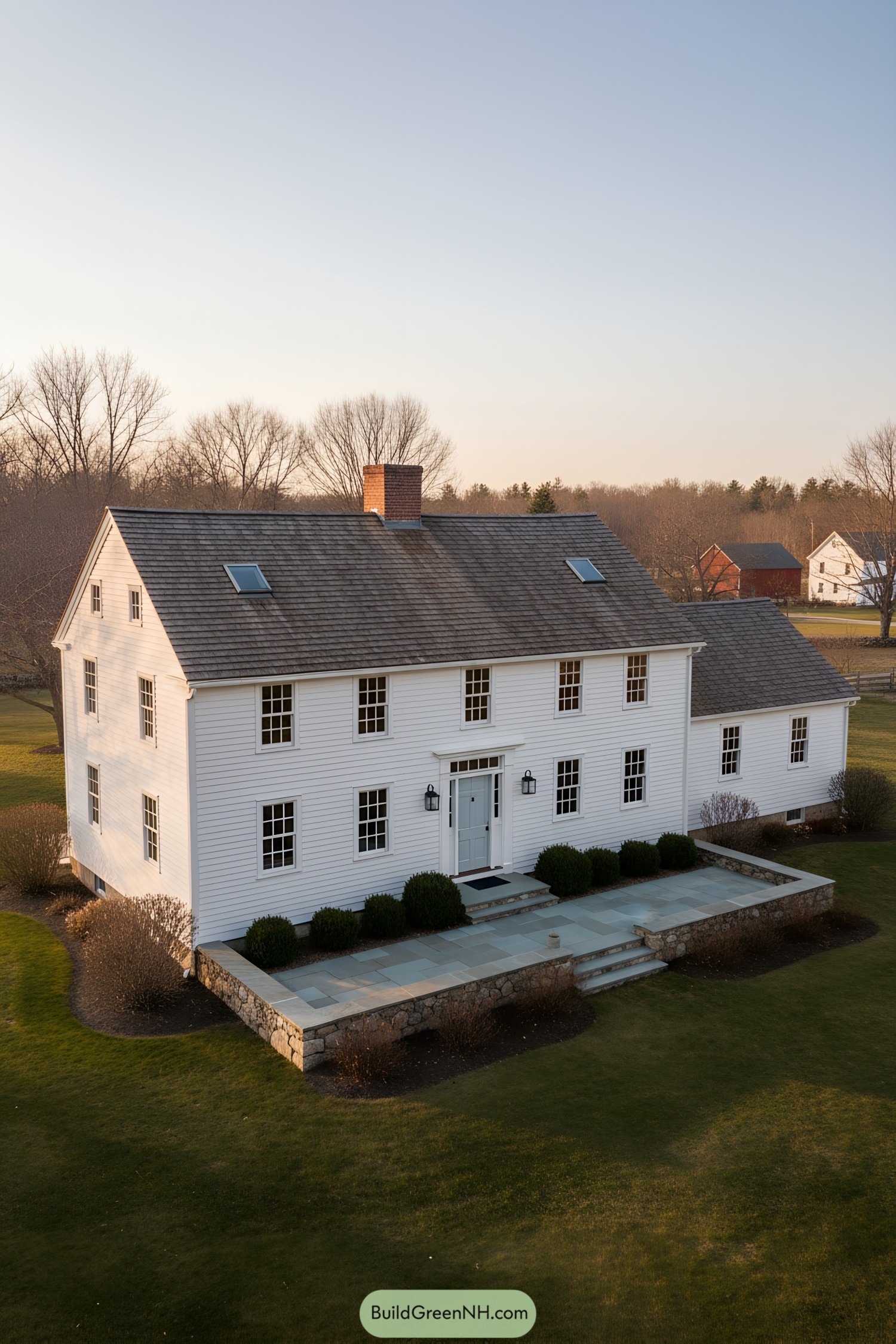 White clapboard colonial with central chimney and stone terrace