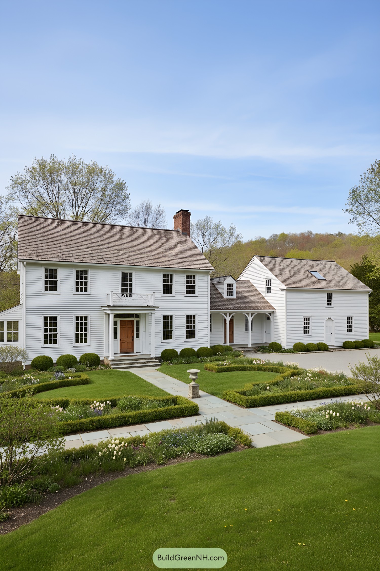 White clapboard colonial farmhouse with breezeway and manicured parterre gardens