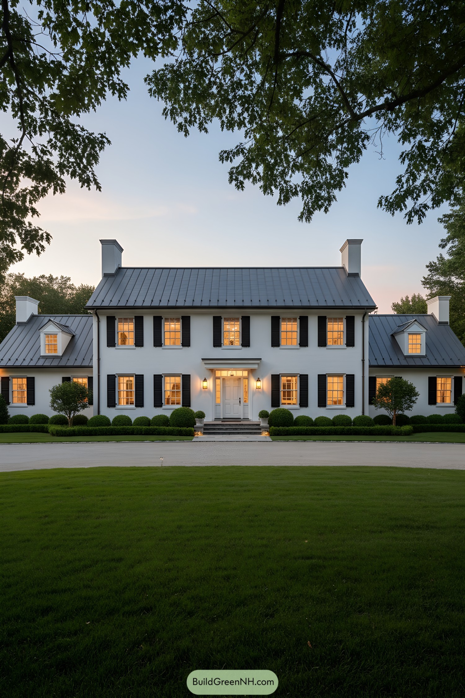 White colonial farmhouse with black shutters and metal roof at dusk