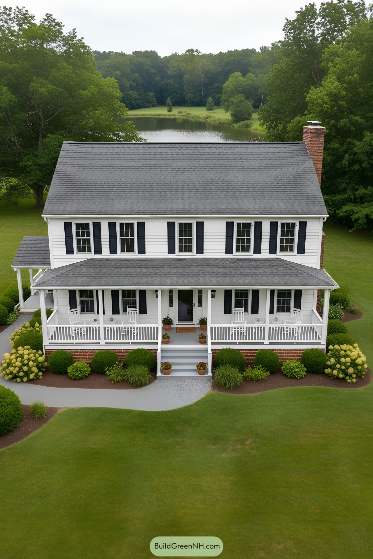 White clapboard colonial with navy shutters, wraparound porch, and brick foundation facing a lake