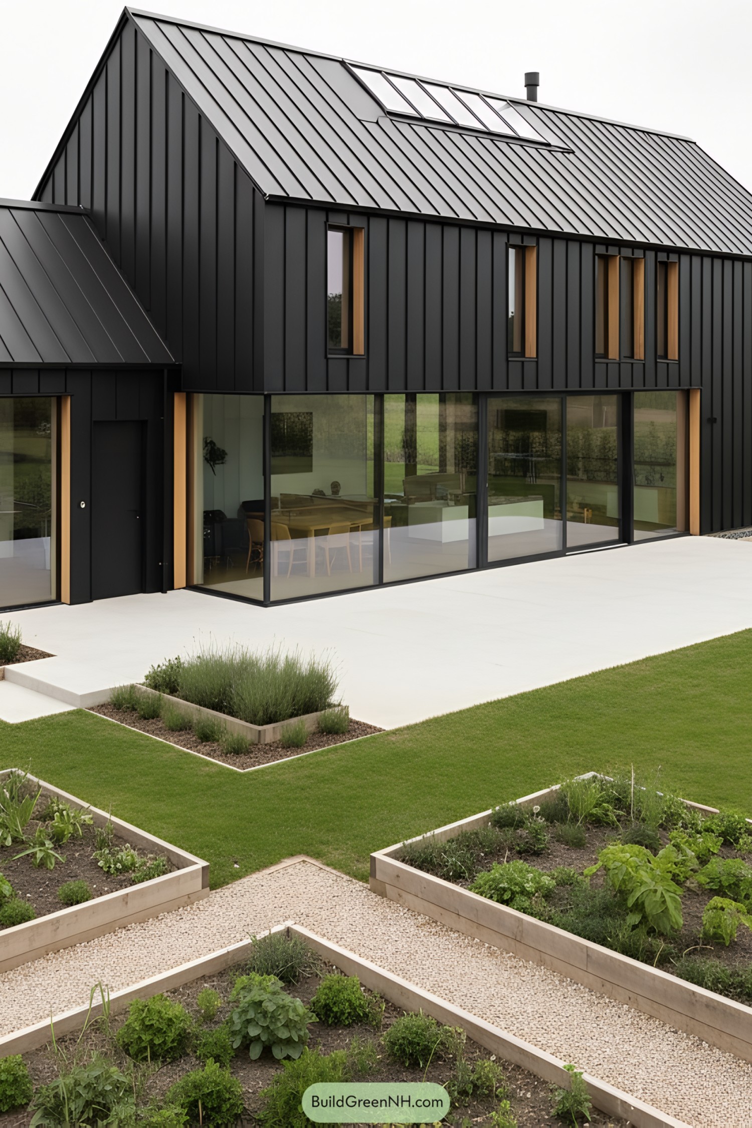 Black metal-clad barn house with broad glass walls and geometric raised beds