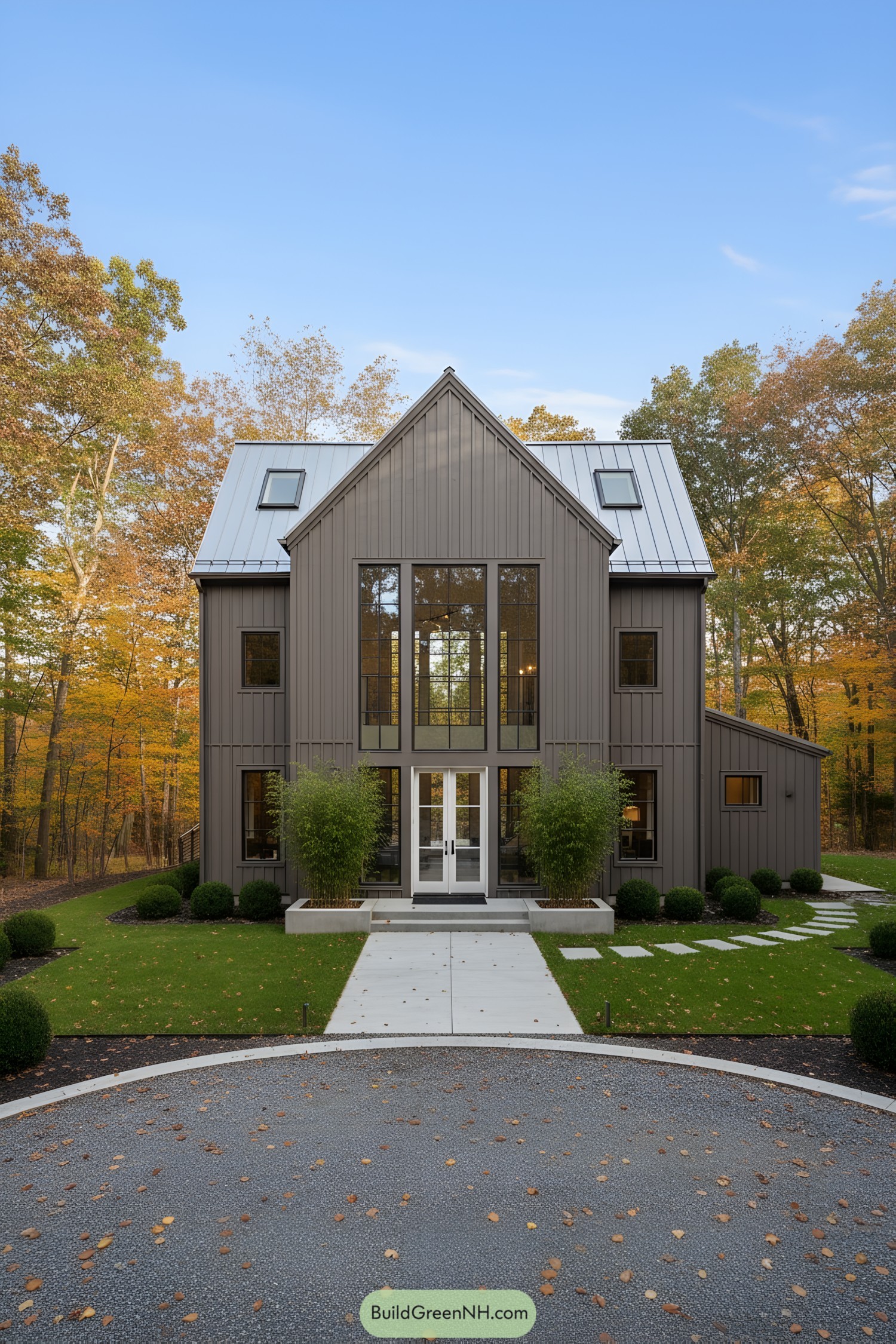 Contemporary barn home with taupe siding, tall central glazing, and a silver metal roof