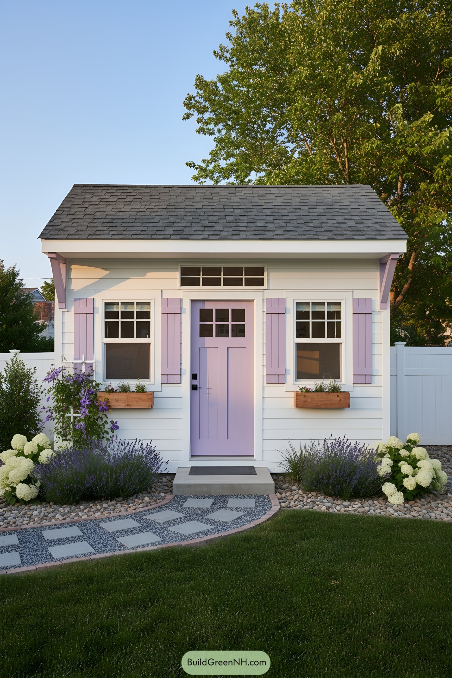 Small white shed with lavender door and shutters, flower boxes, and shingled roof