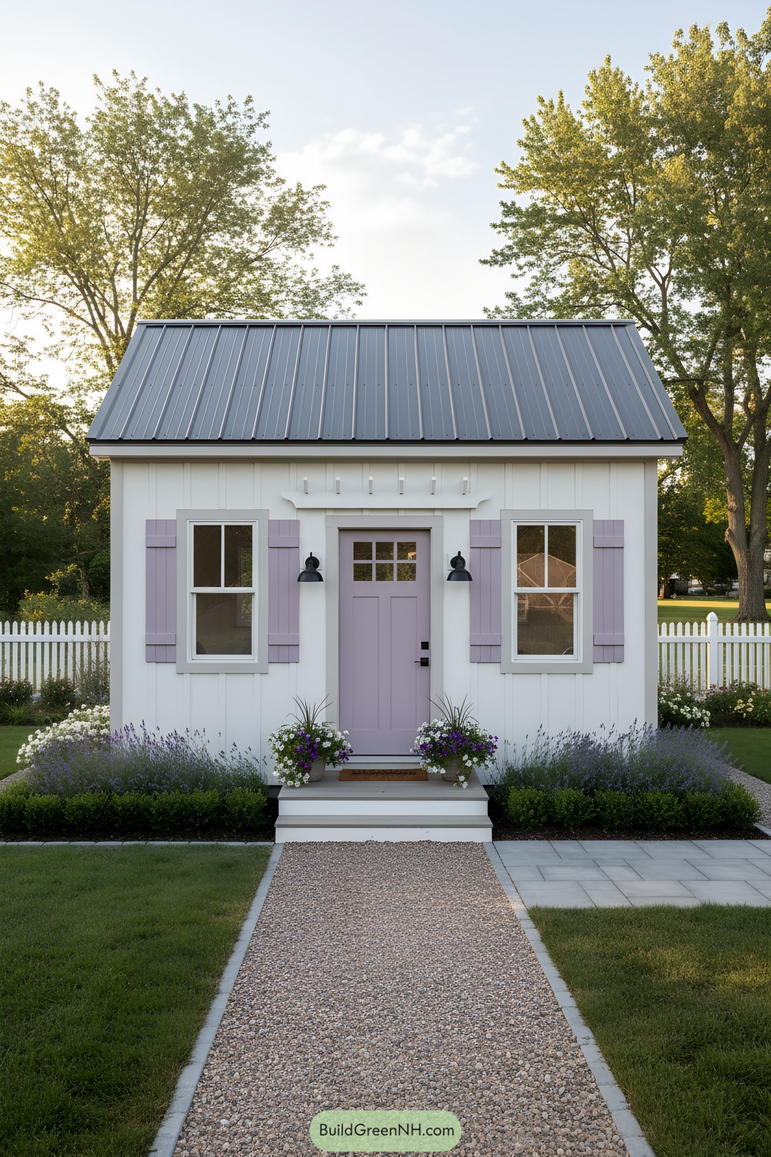 White cottage shed with lavender door and shutters, metal gable roof, and neat flower-lined path