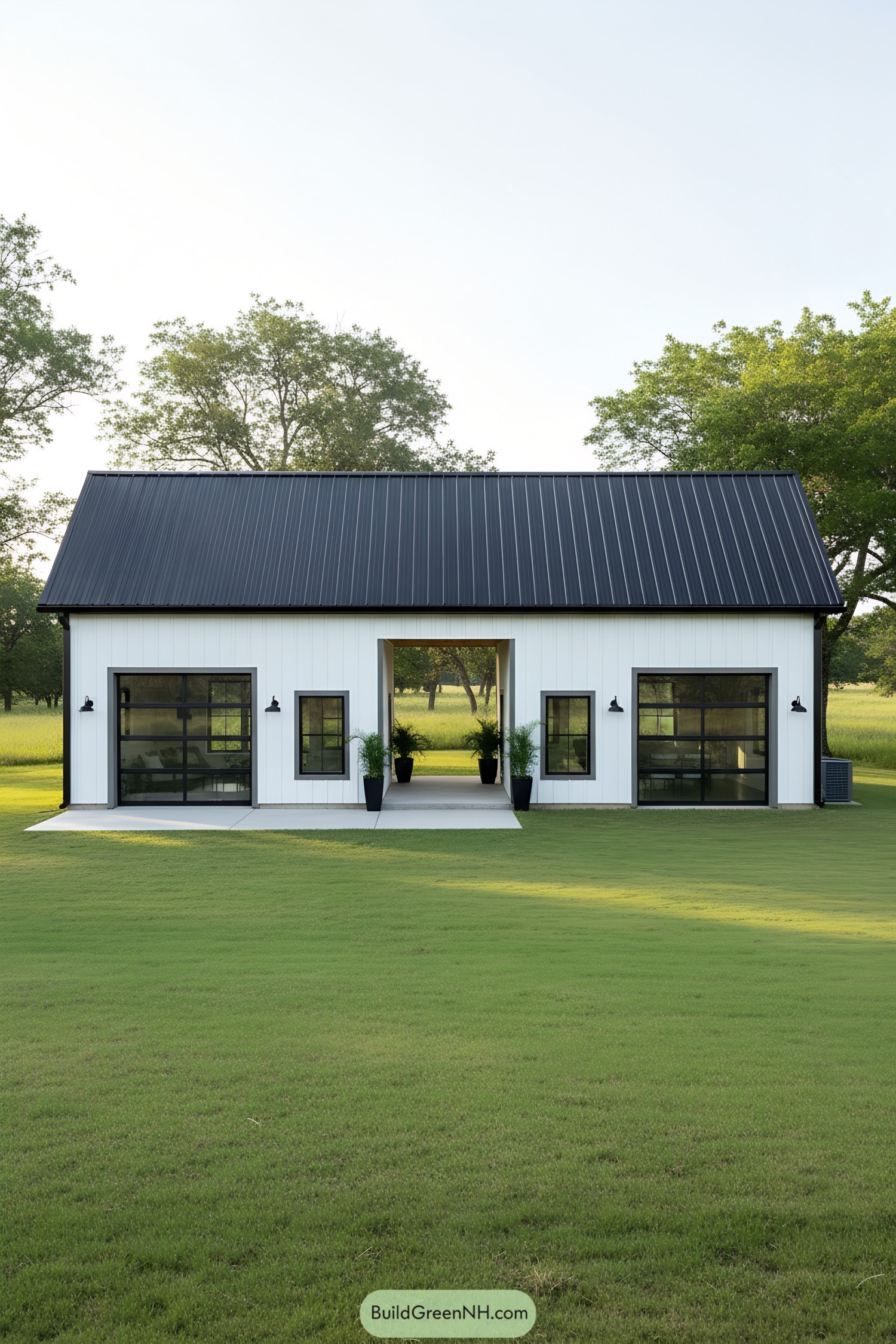 White barndominium with a black roof and a central passageway