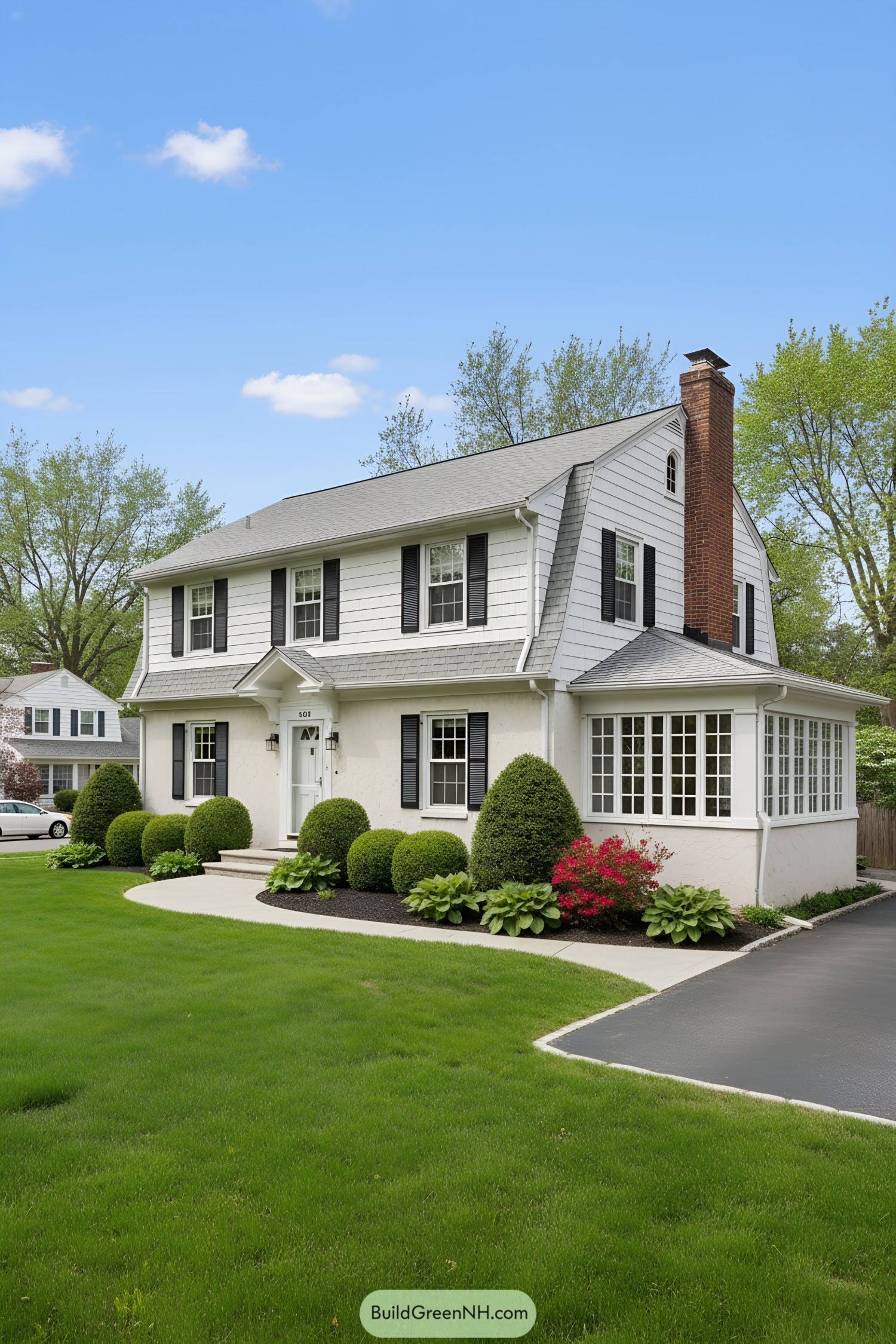 White Dutch Colonial with gambrel roof, black shutters, and side sunroom