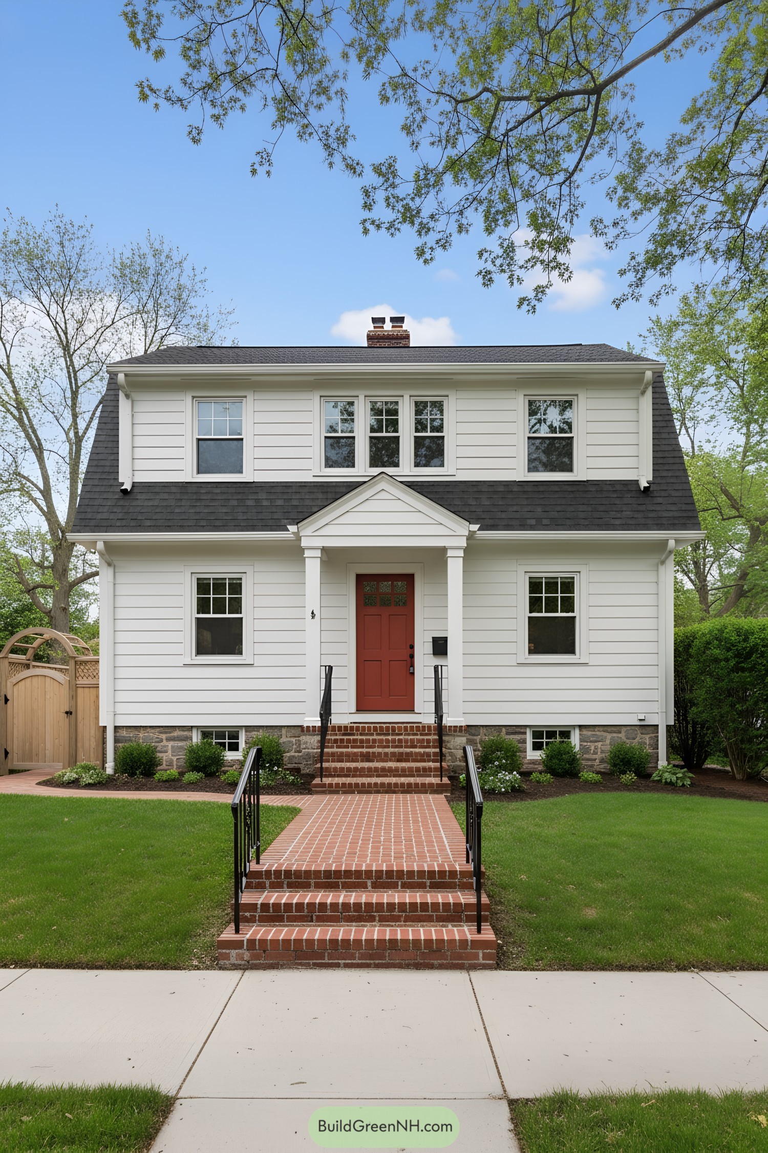 White clapboard Dutch Colonial with gambrel roof and brick stoop