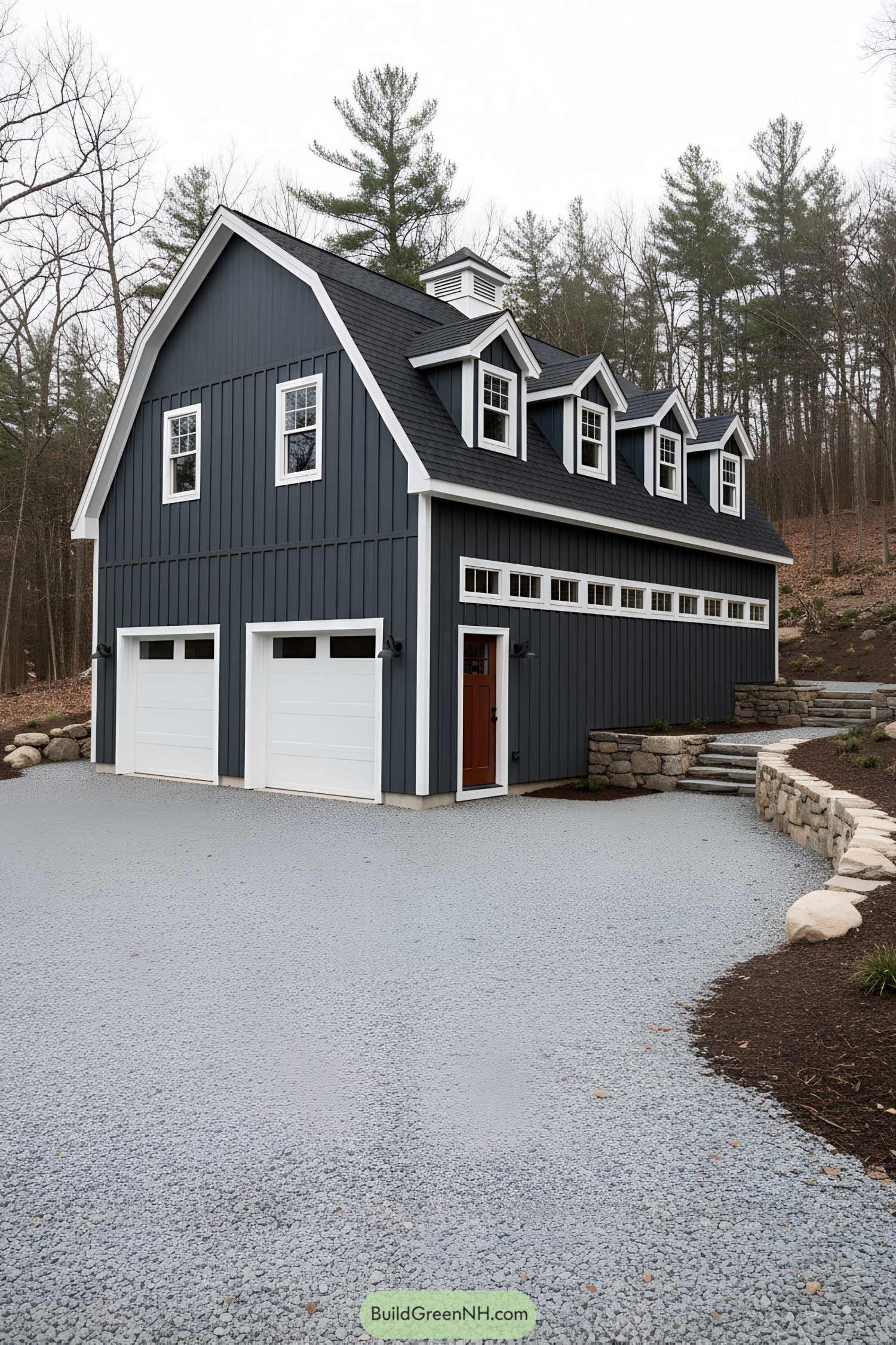 Dark blue gambrel barn with white trim, dormers, and twin garage doors